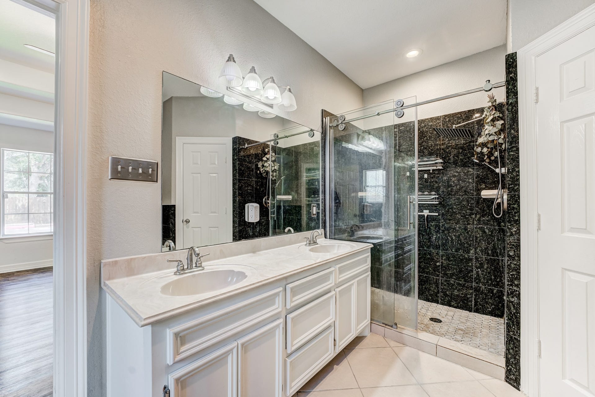 Primary bath with dual-sink vanity, framed mirrors, and oversized shower.