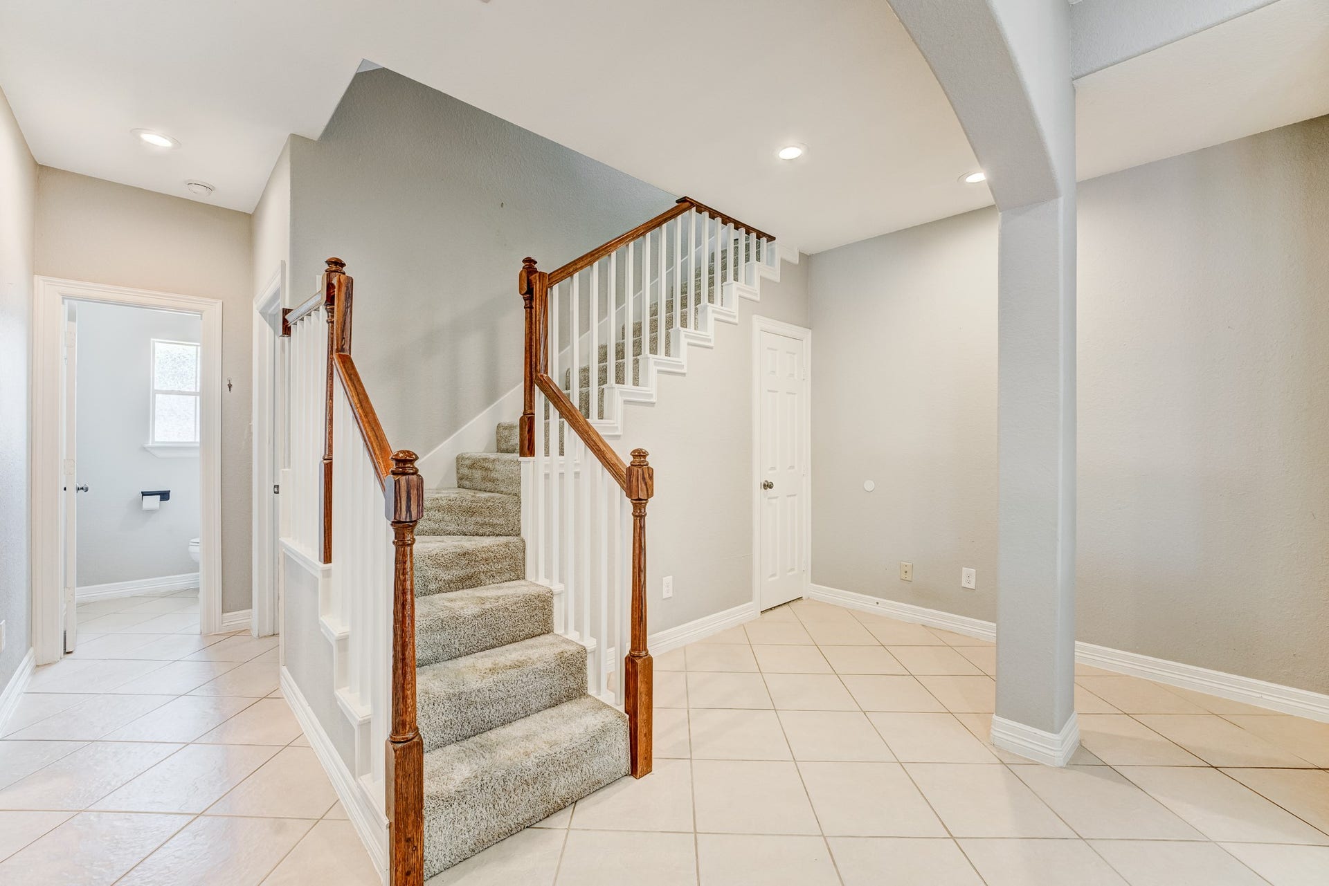 Spacious entryway featuring tile flooring and staircase access.