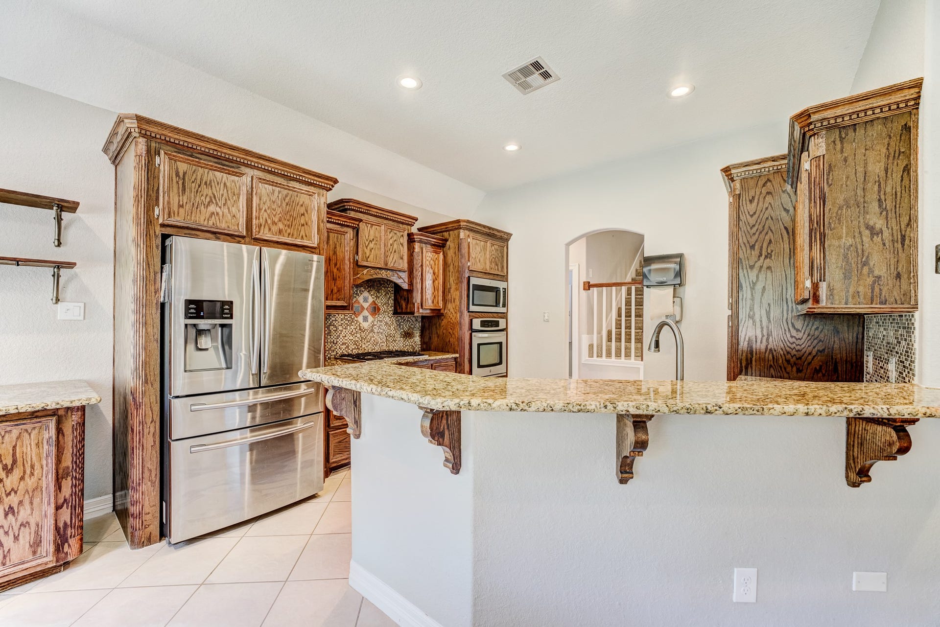 Kitchen featuring granite countertops, raised breakfast bar, and custom cabinetry.