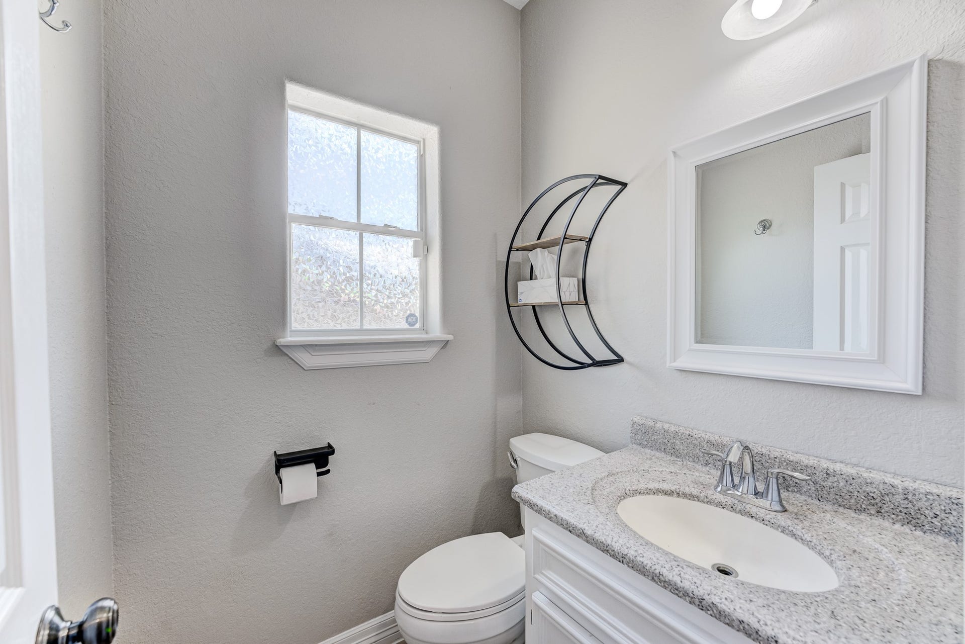 Convenient half bath featuring granite countertops and updated fixtures.