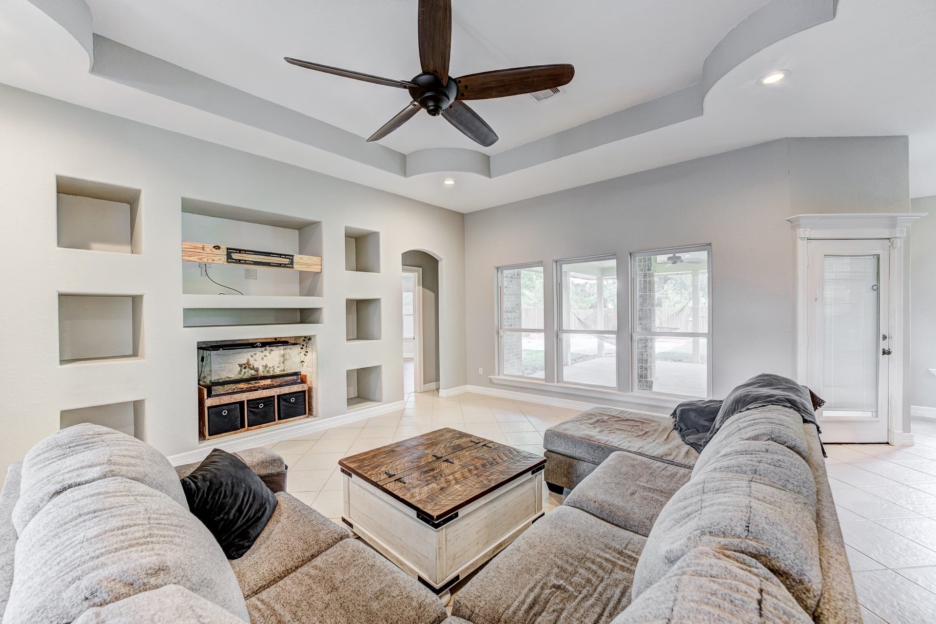 Comfortable family room with tray ceiling, built-ins, and abundant natural light.