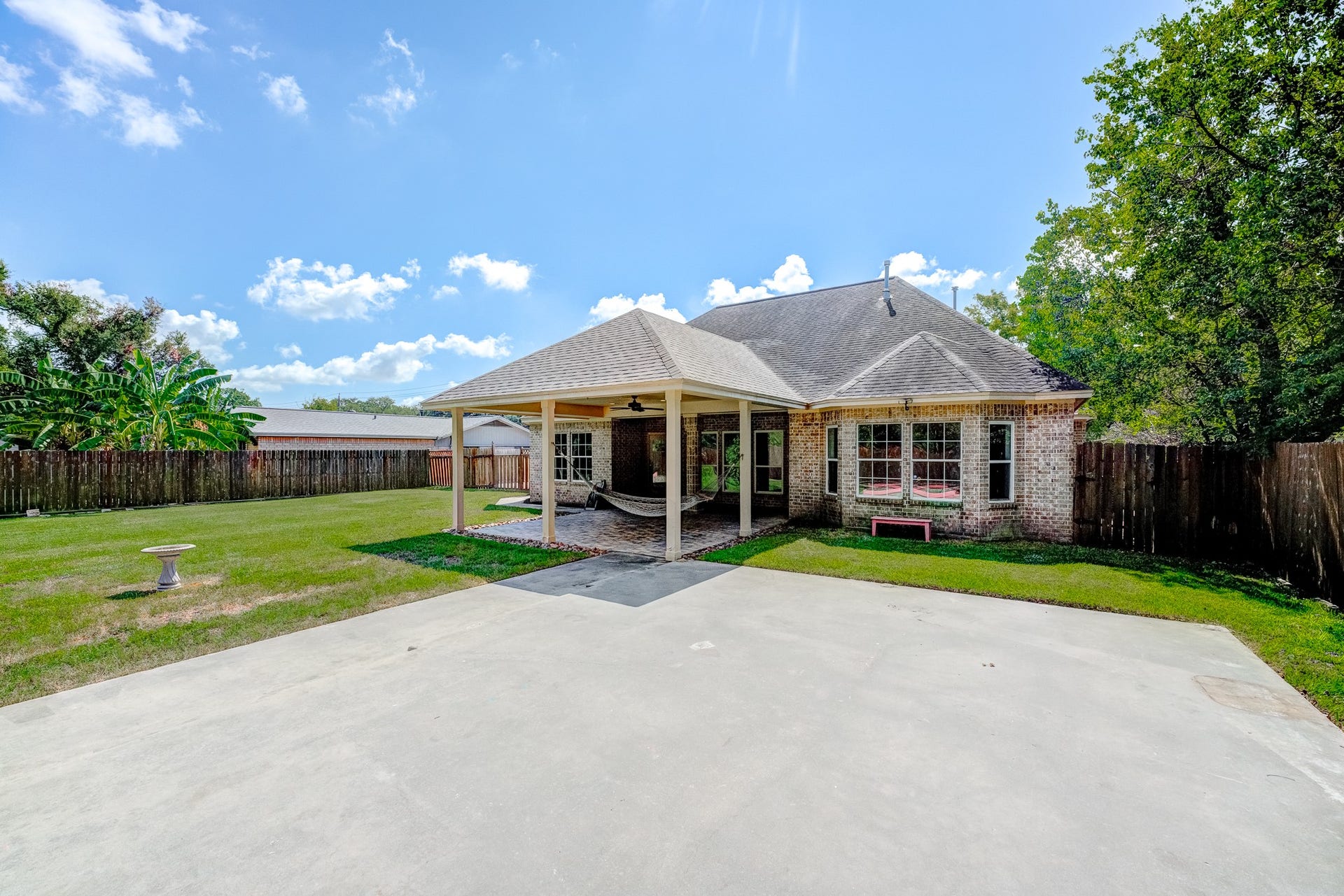 Rear exterior showcasing a large covered patio and generous backyard space.
