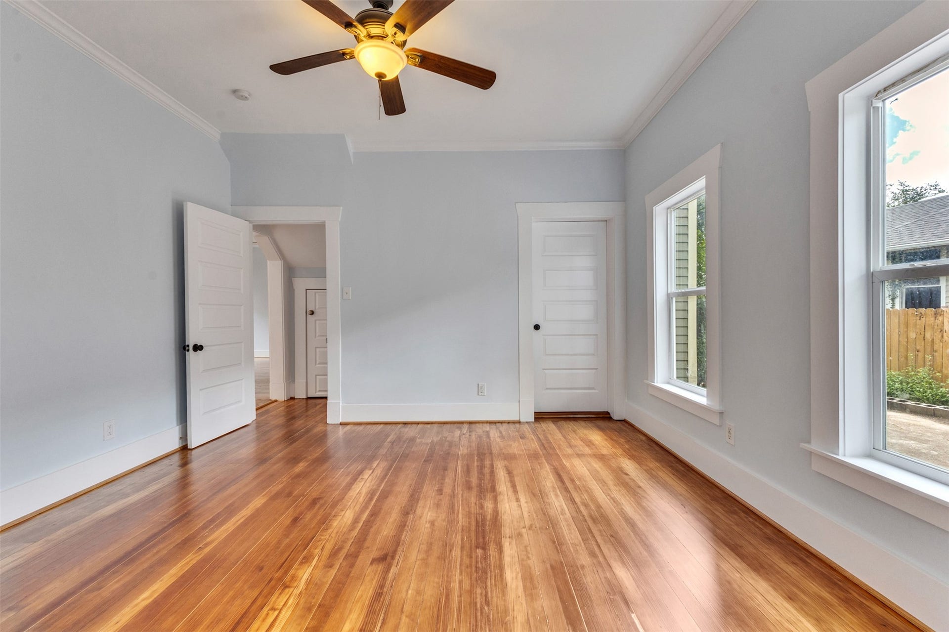 4534 Woodside Street, Houston, TX 77023 Bright and spacious room featuring rich hardwood floors, large windows for natural light, and a ceiling fan for comfort.