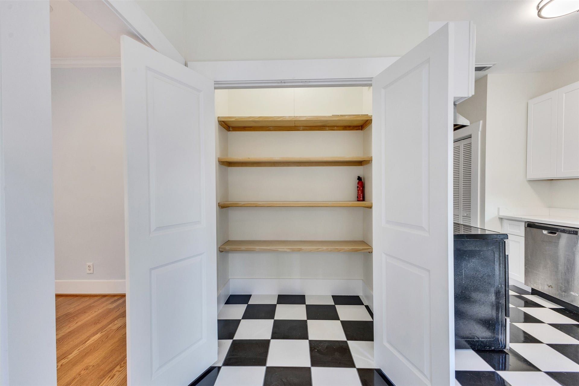 4534 Woodside Street, Houston, TX 77023 Spacious pantry with open shelving and classic black-and-white checkered flooring, blending seamlessly into a modern kitchen with stainless steel appliances.