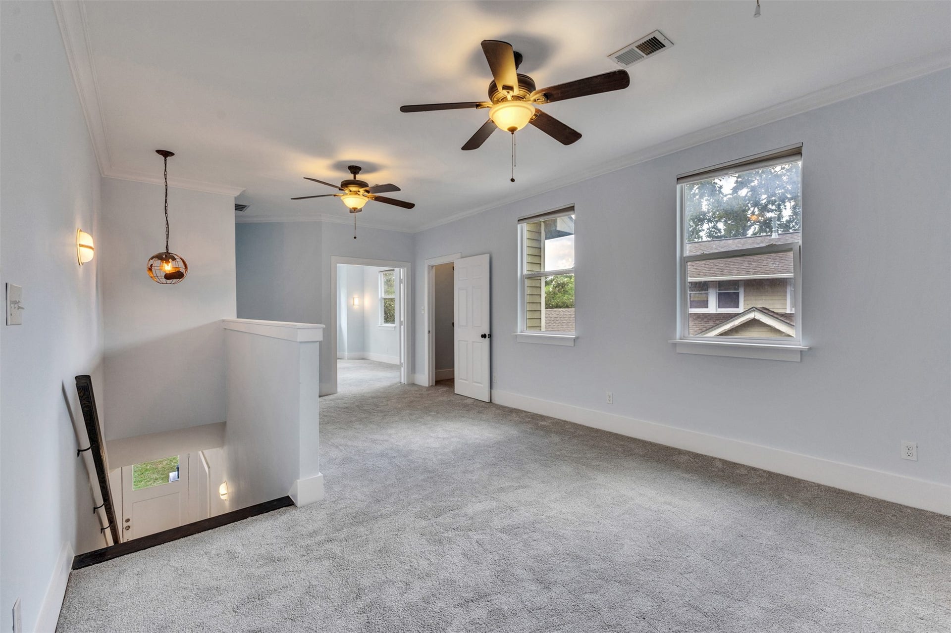 4534 Woodside Street, Houston, TX 77023 Spacious upper-level landing with plush carpeting, abundant natural light, and ceiling fans for comfort.