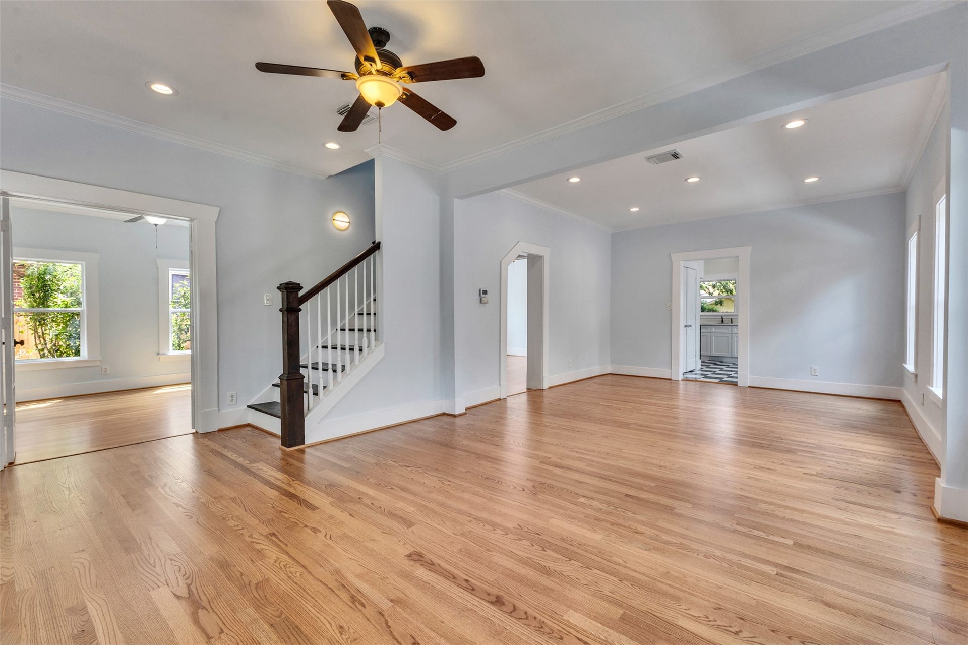 4534 Woodside Street, Houston, TX 77023 Spacious open-concept living area featuring hardwood floors, a ceiling fan, and abundant natural light, with easy access to adjacent rooms and a staircase leading upstairs.