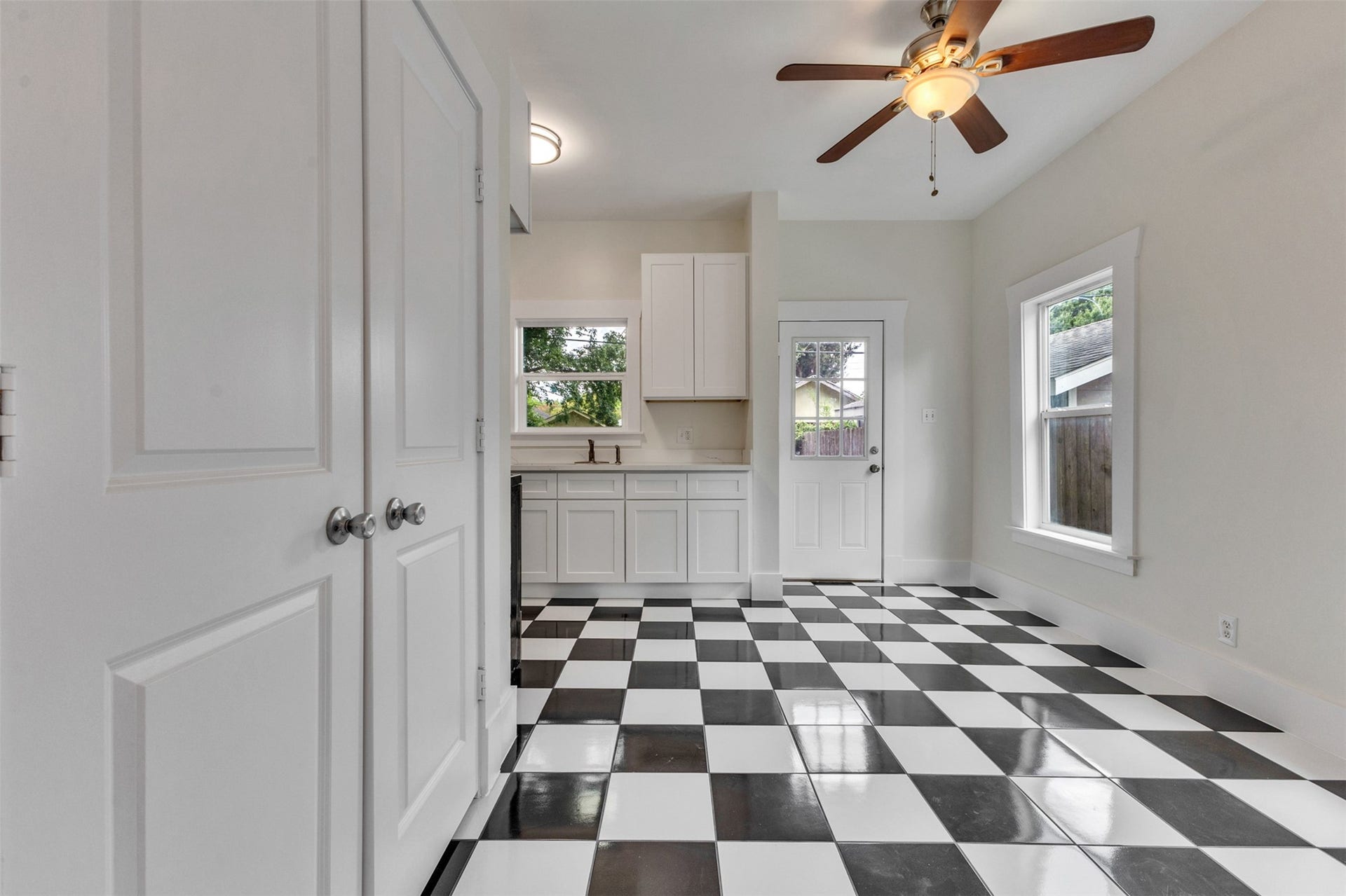 4534 Woodside Street, Houston, TX 77023 Bright kitchen with stylish black and white checkered flooring, modern ceiling fan, and ample natural light from large windows.