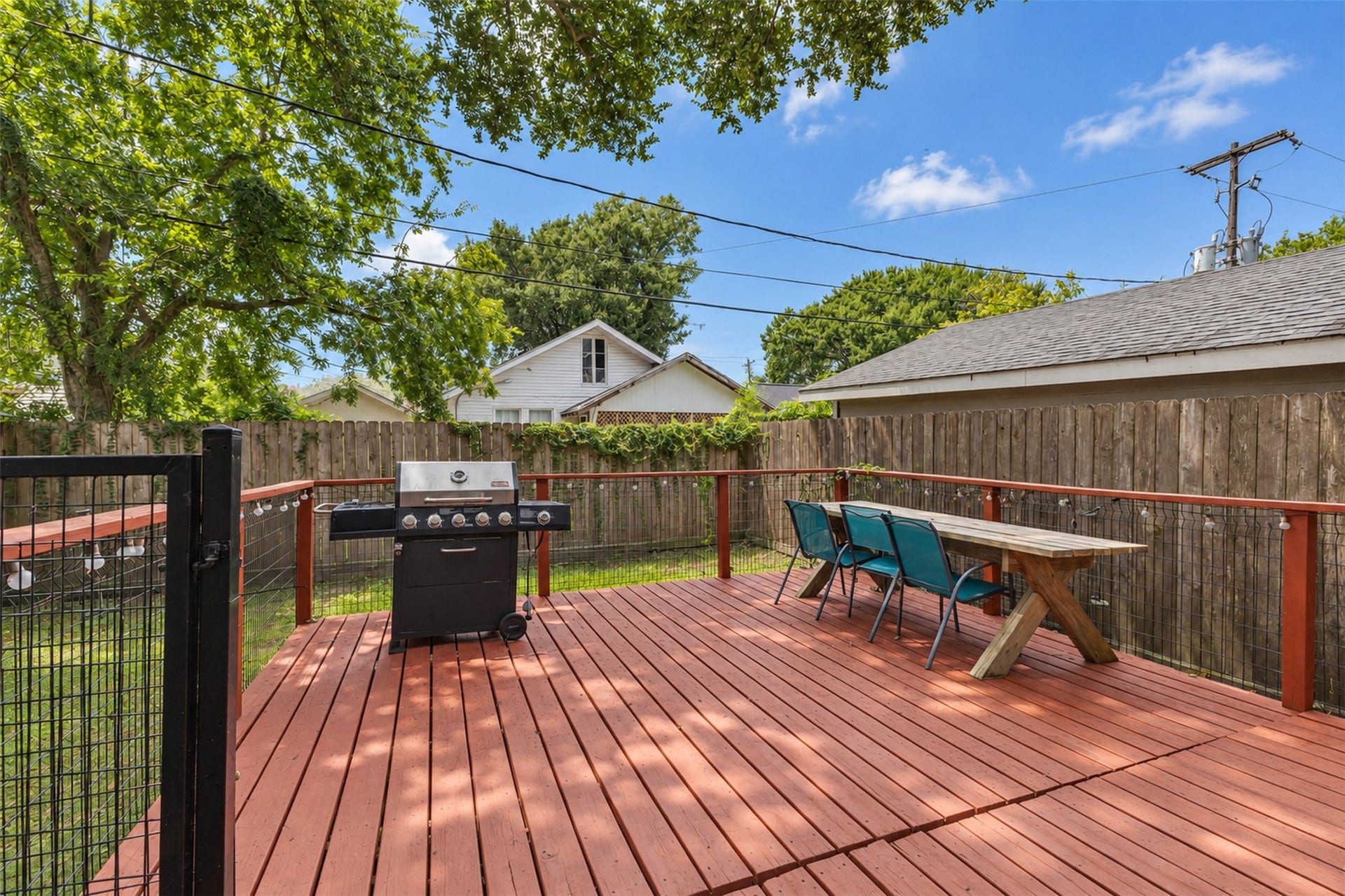 4534 Woodside Street, Houston, TX 77023 Spacious backyard deck perfect for entertaining, featuring a built-in grill and ample seating under the shade of mature trees.