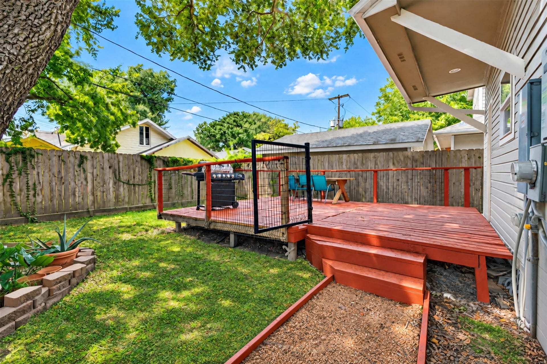 4534 Woodside Street, Houston, TX 77023 Charming backyard featuring a spacious wooden deck perfect for outdoor dining and entertaining, surrounded by lush greenery and mature trees for added privacy.