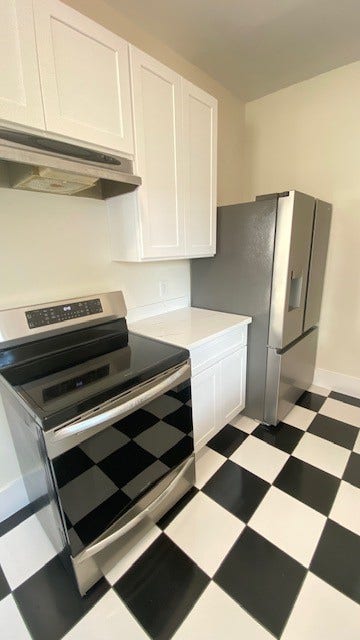 4534 Woodside Street, Houston, TX 77023 Modern kitchen with sleek stainless steel appliances, crisp white cabinetry, and a classic black-and-white checkered floor.