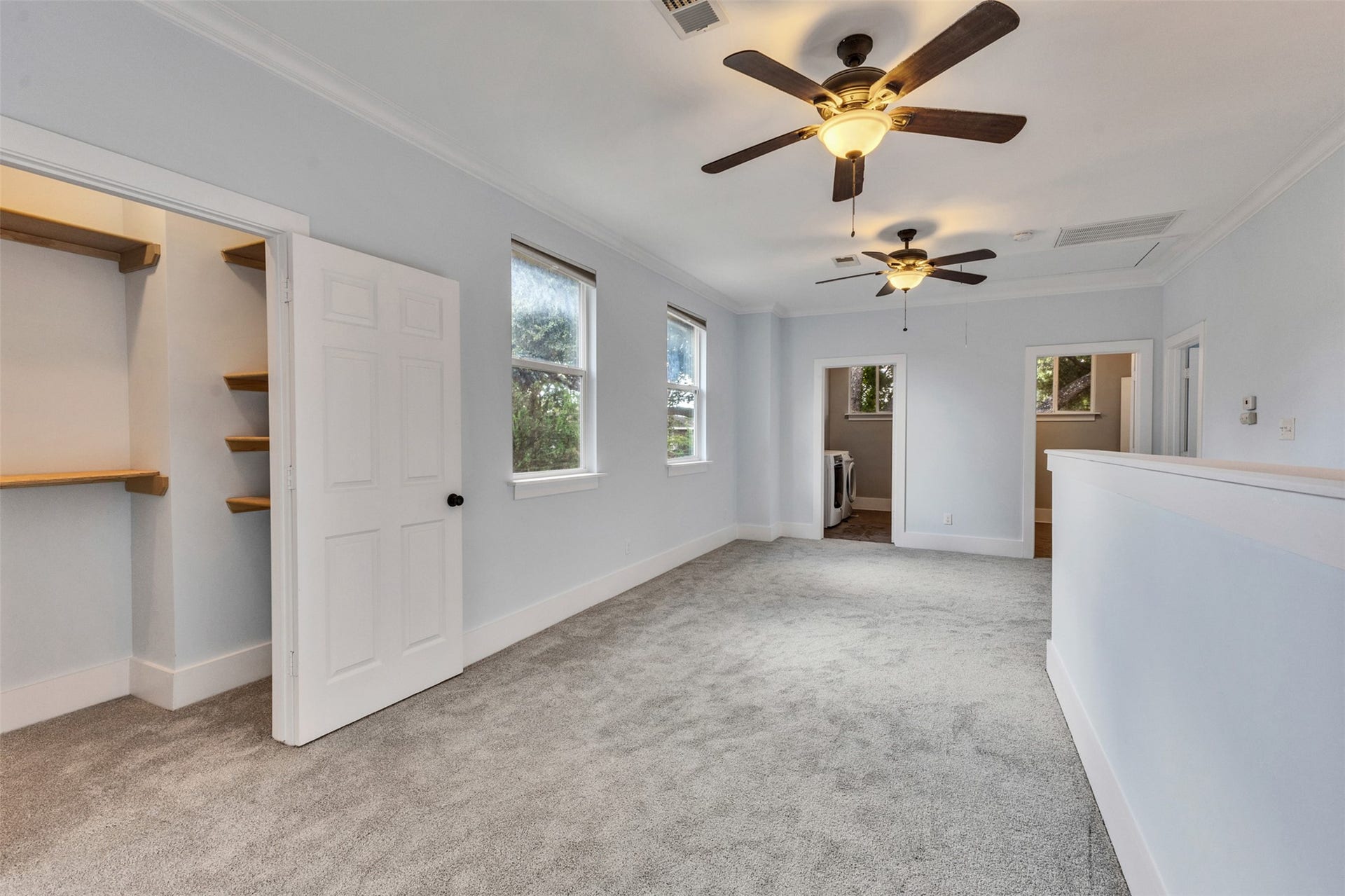 4534 Woodside Street, Houston, TX 77023 Spacious, light-filled room with plush carpeting, featuring two ceiling fans and a convenient walk-in closet.