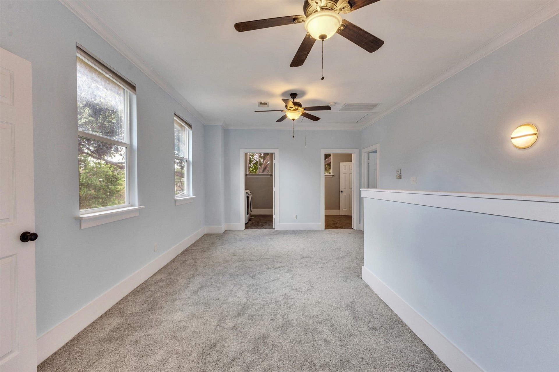 4534 Woodside Street, Houston, TX 77023 Spacious room with soft carpeting, neutral walls, and ample natural light from multiple windows, featuring ceiling fans for added comfort.