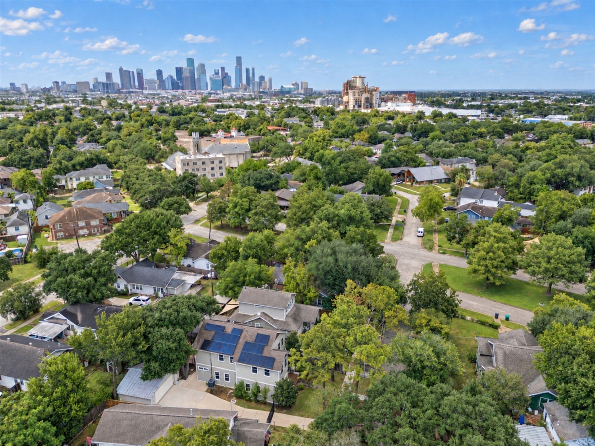 4534 Woodside Street, Houston, TX 77023 Charming neighborhood with lush greenery, offering a serene residential feel with convenient proximity to the vibrant city skyline in the distance.