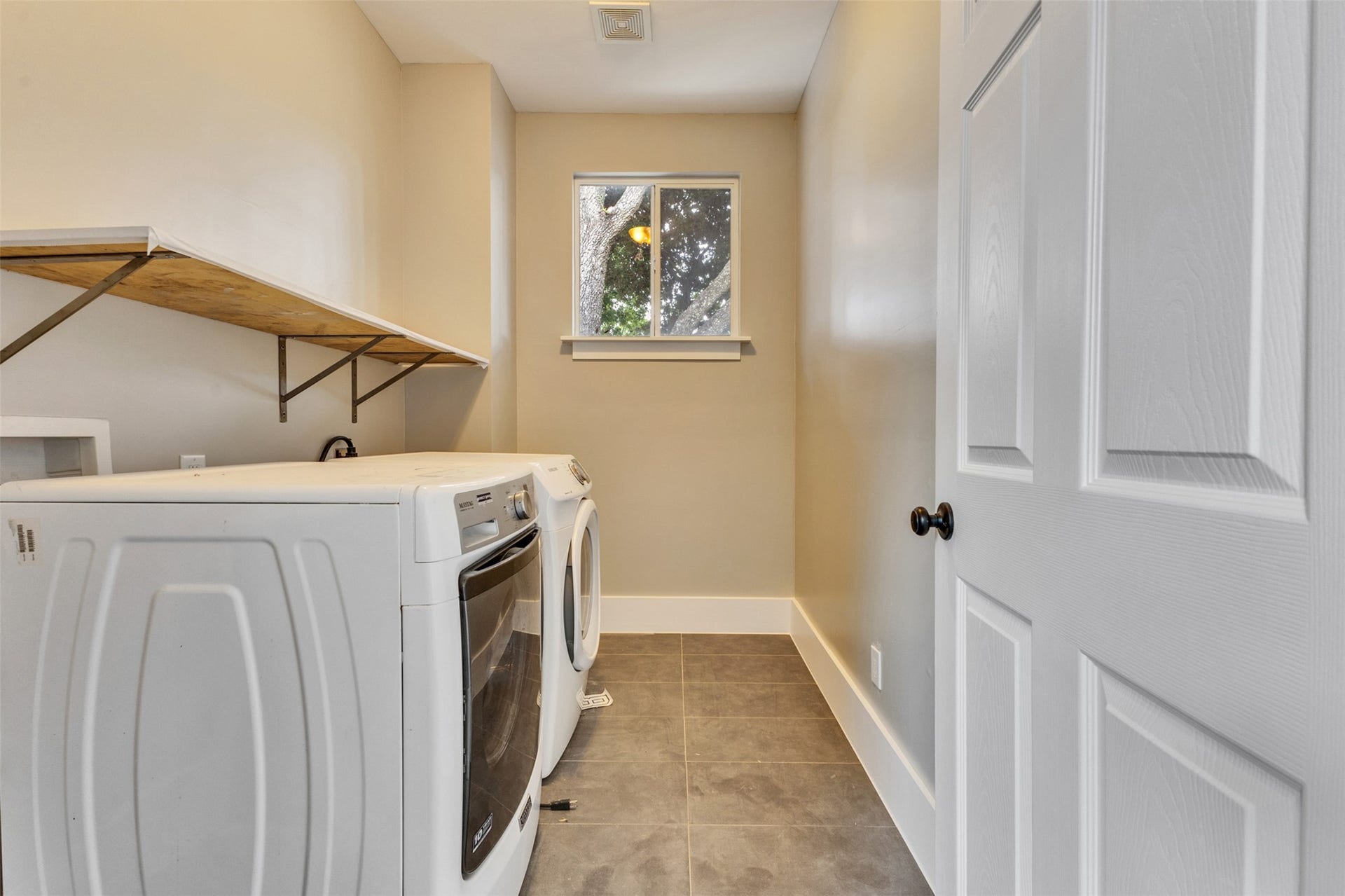 4534 Woodside Street, Houston, TX 77023 Modern laundry room with sleek appliances, ample storage, and natural light from a large window.