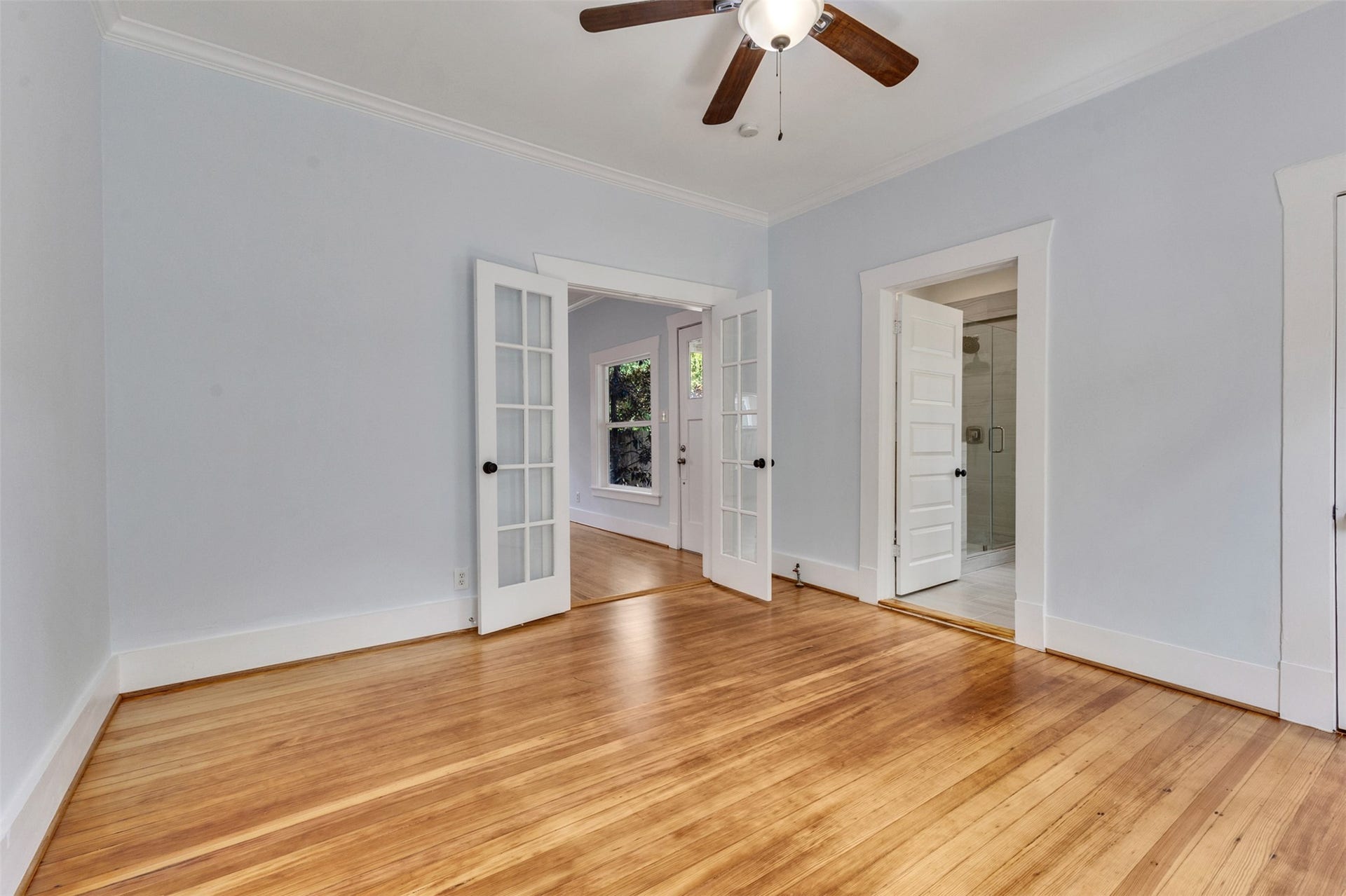 4534 Woodside Street, Houston, TX 77023 Spacious room with beautiful hardwood floors, elegant French doors, and abundant natural light, offering a warm and inviting atmosphere.