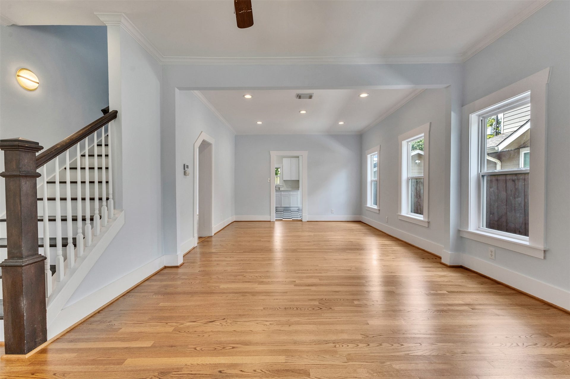 4534 Woodside Street, Houston, TX 77023 Spacious open-plan living area with beautiful hardwood floors, abundant natural light from multiple windows, and a classic staircase leading upstairs.