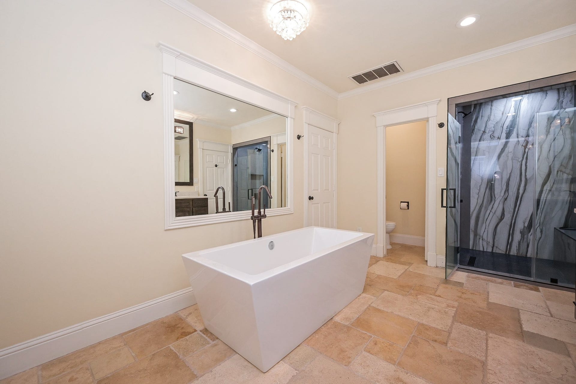 This view shows a spacious glass-enclosed shower with striking marble accents.