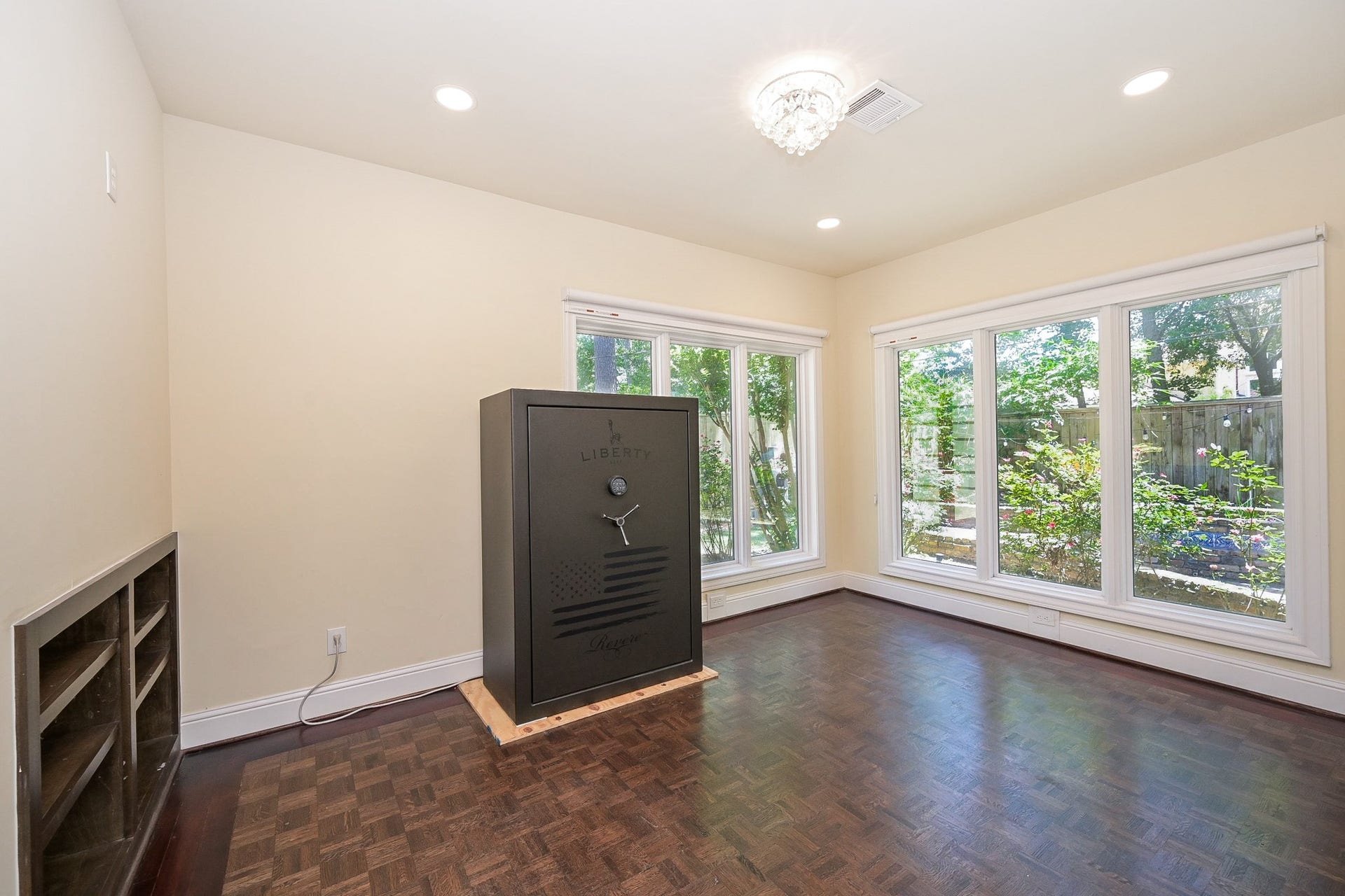 This bright room located in the primary bedroom features large windows with garden views, hardwood floors, recessed lighting, and a secure safe, ideal for a study or private retreat.