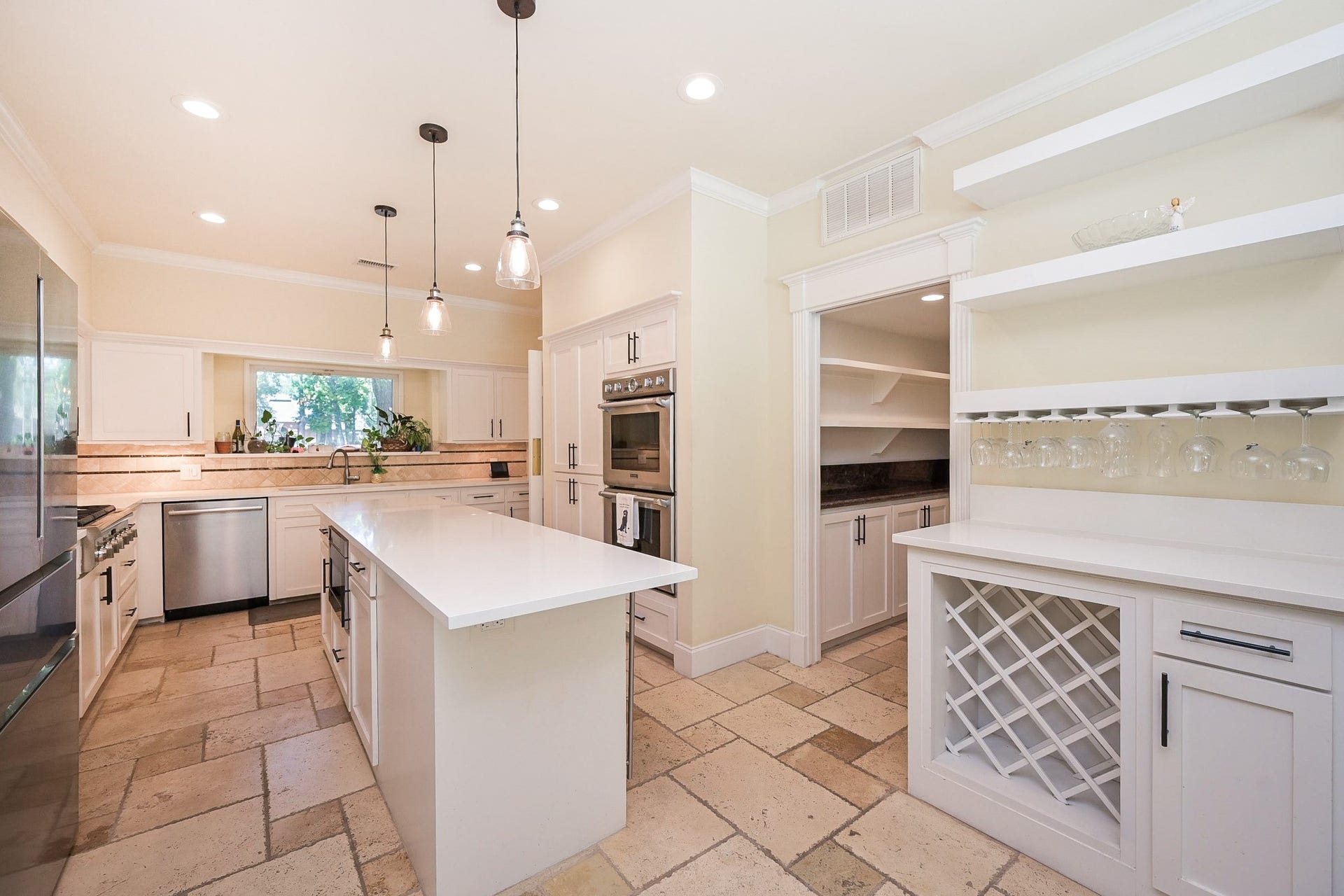 This spacious kitchen features modern appliances, a large central island with pendant lighting, and microwave drawer. It includes a built-in wine rack and walk in wet bar.