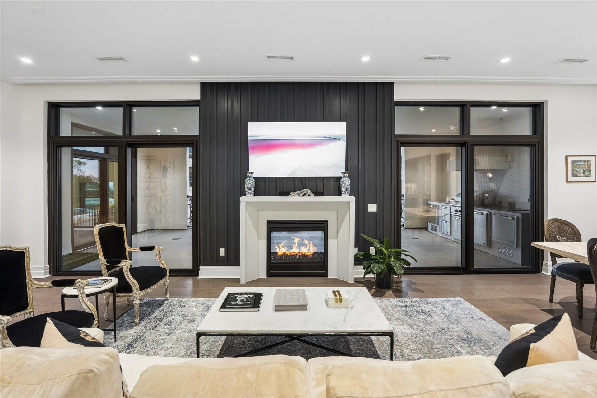 6017 Memorial Drive, #505, Houston, TX 77007 A distinctive architectural feature of this residence is the double-sided fireplace, creating an elegant focal point for both the interior living area and private terrace. Framed by a dramatic accent wall and flanked by expansive glass doors, the fireplace enhances the seamless connection between indoor and outdoor living. Beyond the glass, a fully equipped summer kitchen offers an exceptional setting for entertaining.
