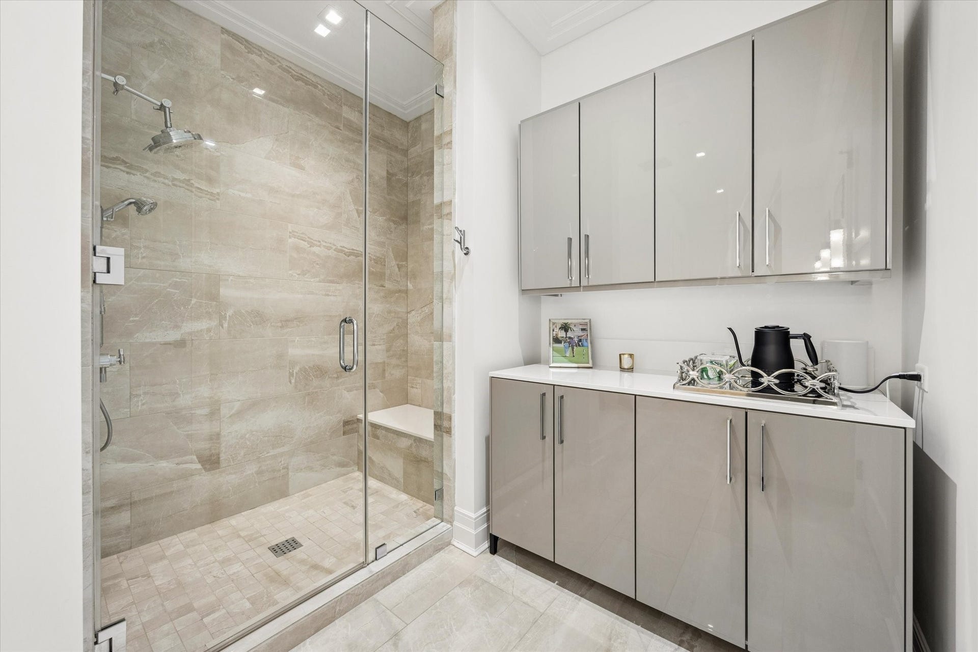 6017 Memorial Drive, #505, Houston, TX 77007 The primary bathroom features an elegantly designed walk-in shower surrounded by beautiful porcelain tile in warm, natural tones. Frameless glass doors, polished chrome Brizo fixtures, and a built-in shower bench create a refined, spa-inspired experience. Adjacent contemporary cabinetry provides generous storage while maintaining the clean architectural lines and sophisticated European aesthetic found throughout the residence.