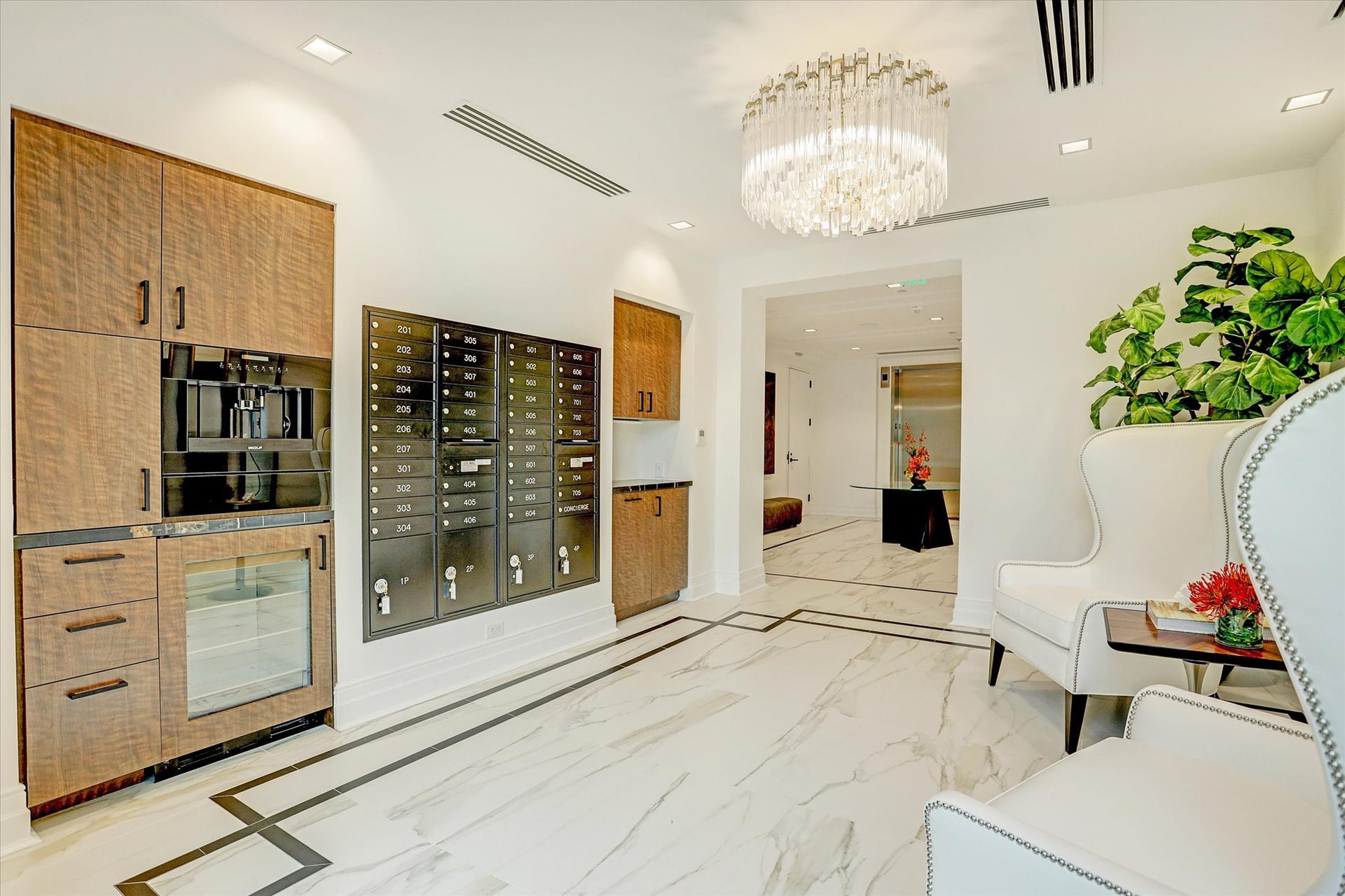 6017 Memorial Drive, #505, Houston, TX 77007 The Sophie's thoughtfully designed lobby amenities elevate everyday living with an exceptional level of convenience and sophistication. Elegant stone flooring, warm wood cabinetry, and a dramatic crystal chandelier create a refined setting. A beautifully integrated coffee station and dedicated resident mailboxes provide practical conveniences, while comfortable seating and carefully selected finishes reinforce the building's exclusive boutique atmosphere and attentive residential experience.