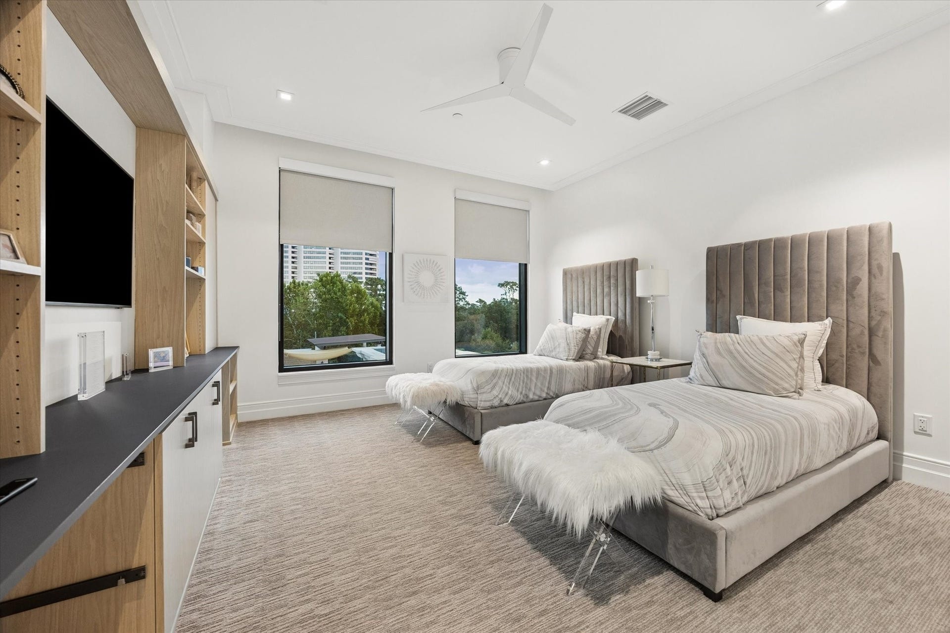 6017 Memorial Drive, #505, Houston, TX 77007 This beautifully appointed secondary bedroom offers a bright, inviting retreat with generous proportions and a refined contemporary aesthetic. Large windows provide natural light and views of the surrounding greenery, while a tray ceiling with recessed lighting adds architectural interest. Custom built-in cabinetry provides attractive display space and convenient storage. The room comfortably accommodates two beds, offering exceptional flexibility for family or guests.