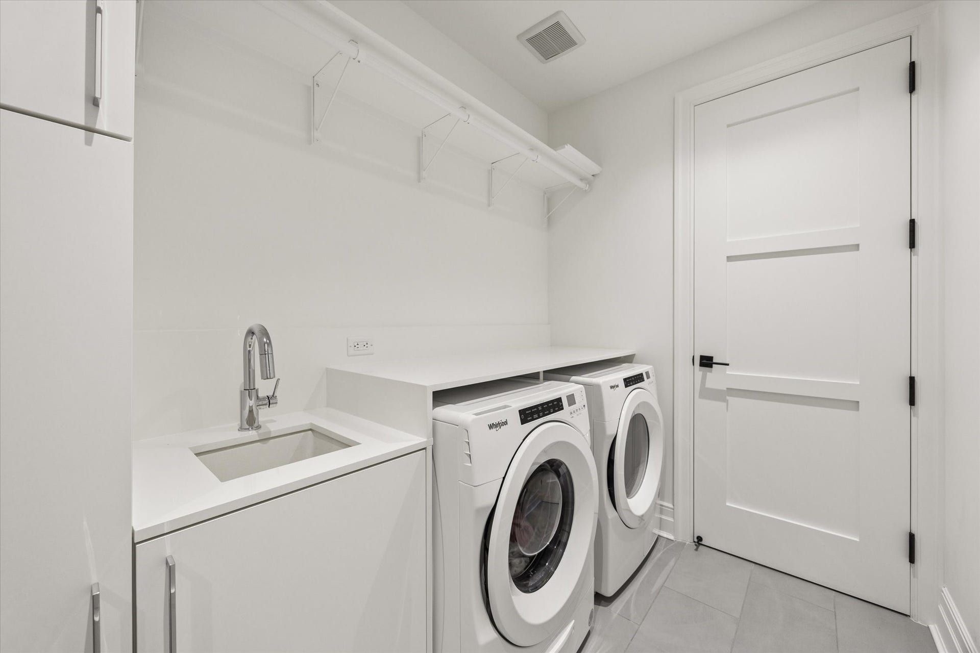 6017 Memorial Drive, #505, Houston, TX 77007 A thoughtfully designed private utility room adds everyday convenience to this luxury residence. Equipped with a full-size front-loading washer and dryer, the space features a dedicated utility sink, generous countertop space, and additional shelving for storage and organization. Crisp white cabinetry, contemporary tile flooring, and clean architectural finishes create a practical, well-appointed laundry area that complements the home's refined design.