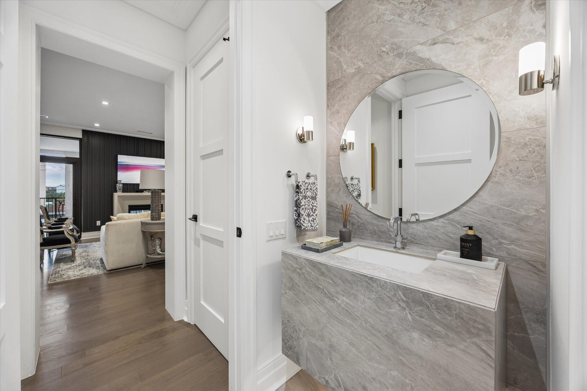6017 Memorial Drive, #505, Houston, TX 77007 An elegantly appointed powder room showcases the residence's attention to detail and refined contemporary aesthetic. Dramatic stone finishes extend across the vanity and accent wall, creating a beautifully coordinated design. A large circular mirror, polished chrome fixtures, and sophisticated wall sconces complete the space. Conveniently positioned near the main living areas, this stylish powder room offers an impressive experience for guests.