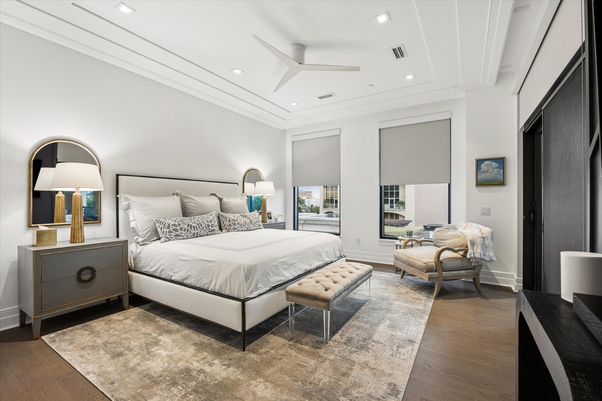 6017 Memorial Drive, #505, Houston, TX 77007 The spacious primary bedroom offers a serene retreat defined by understated luxury and contemporary European elegance. A beautifully detailed tray ceiling with recessed lighting and ceiling fan adds architectural interest, while rich hardwood flooring brings warmth to the sophisticated interior. Generous windows provide natural light, and the thoughtfully proportioned layout comfortably accommodates a king-size bed and sitting area, creating an inviting private sanctuary.