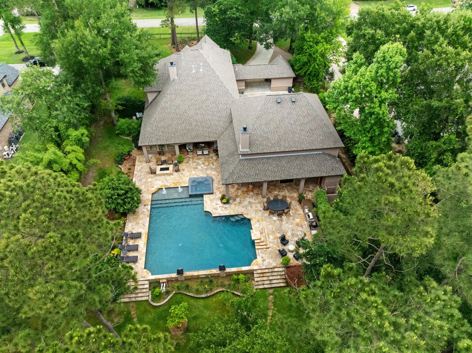 A bird's-eye view showcasing the incredible scale of this private 1-acre waterfront estatefrom the resort-style pool and over 2,000 SF of travertine entertaining space to the multiple outdoor living areas surrounded by mature trees.
