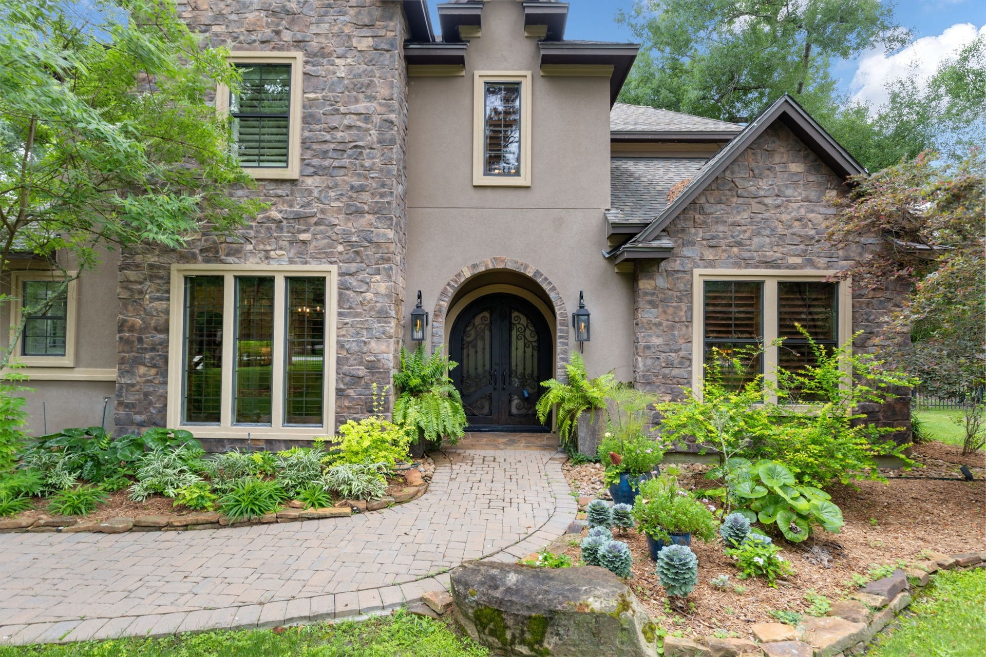 Inviting paver walkway leading to a grand arched front porch with classic gas lanterns create a warm first impression.