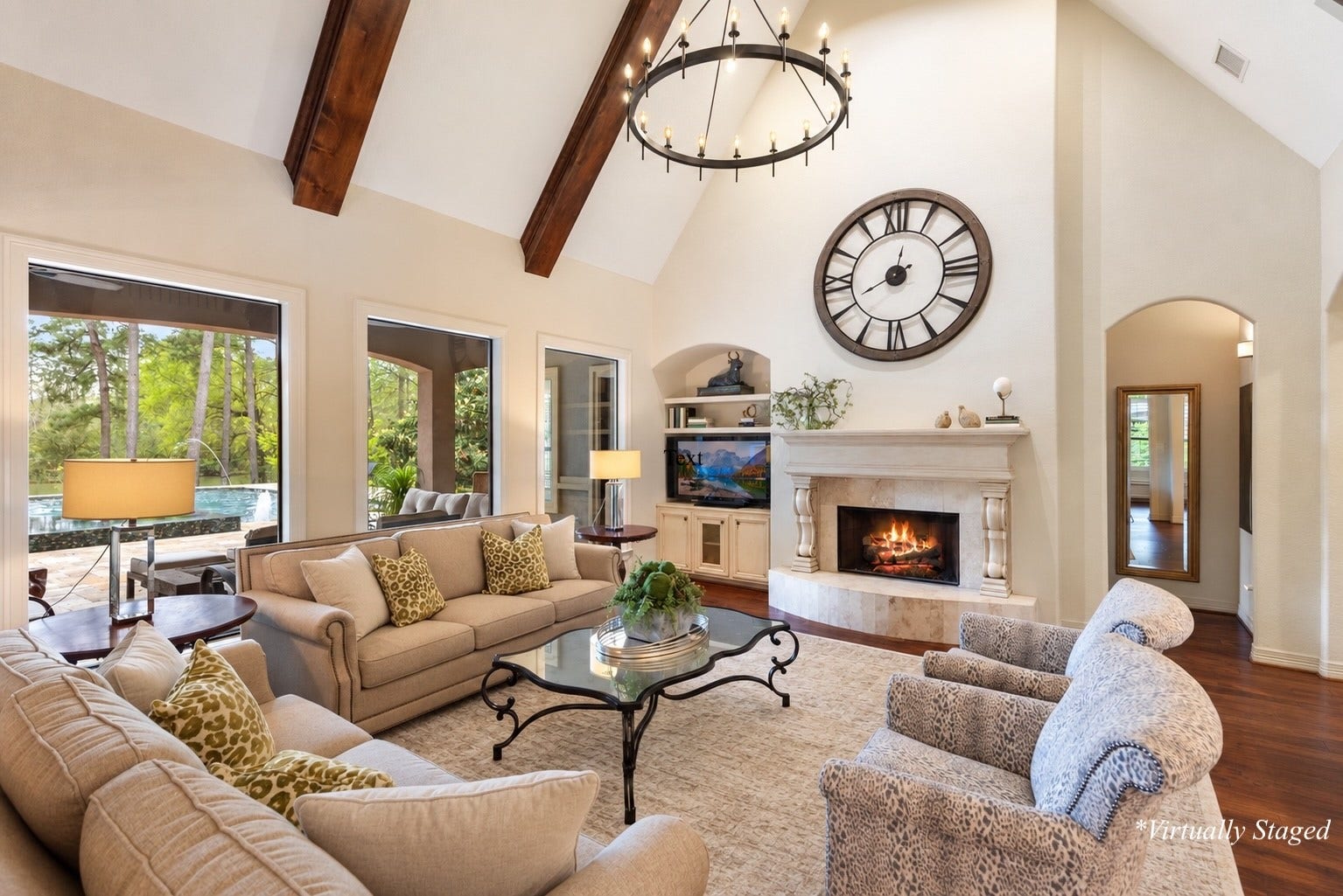 Dramatic Family Room with soaring cathedral beam ceiling, floor-to-ceiling windows framing the pool and lake, Travertine gas fireplace, custom built-ins, and exceptional architectural character. *Partially Virtually Staged Decor
