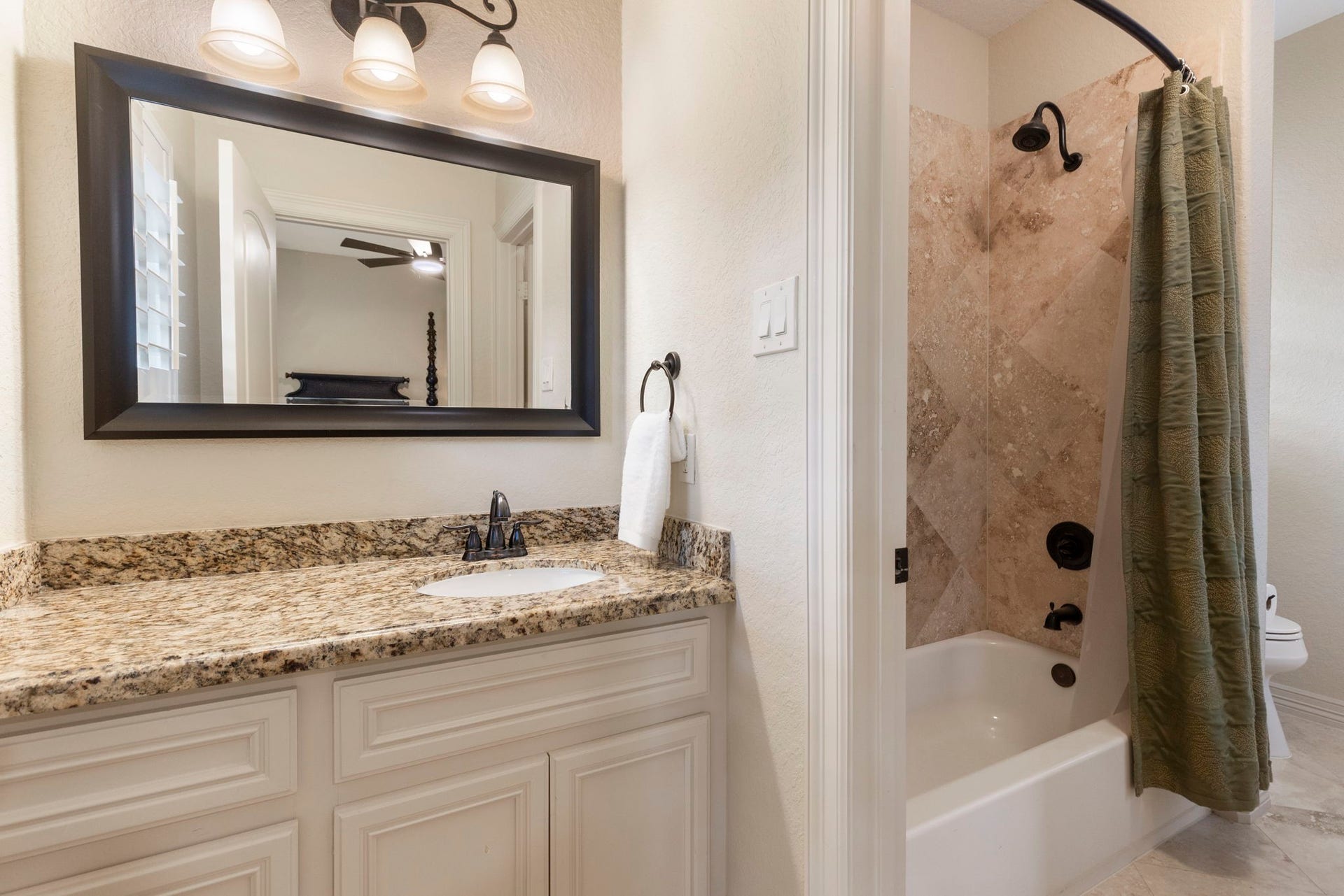 Well-appointed bath serving two bedrooms with separate private vanity areas, granite countertops, Travertine flooring, ample storage and a shared tub/shower space.