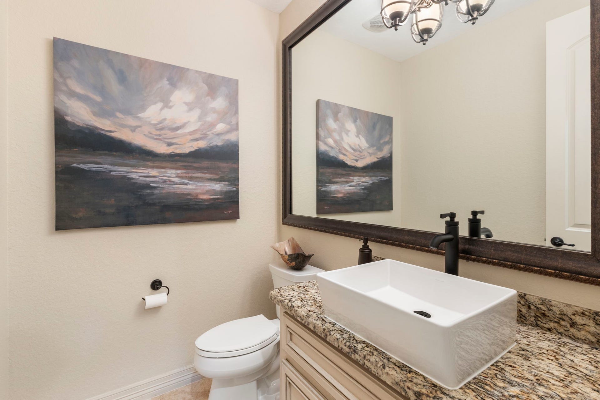 Beautiful powder bath with Travertine flooring, raised vessel sink, and granite countertop - one of two powder baths in the home.