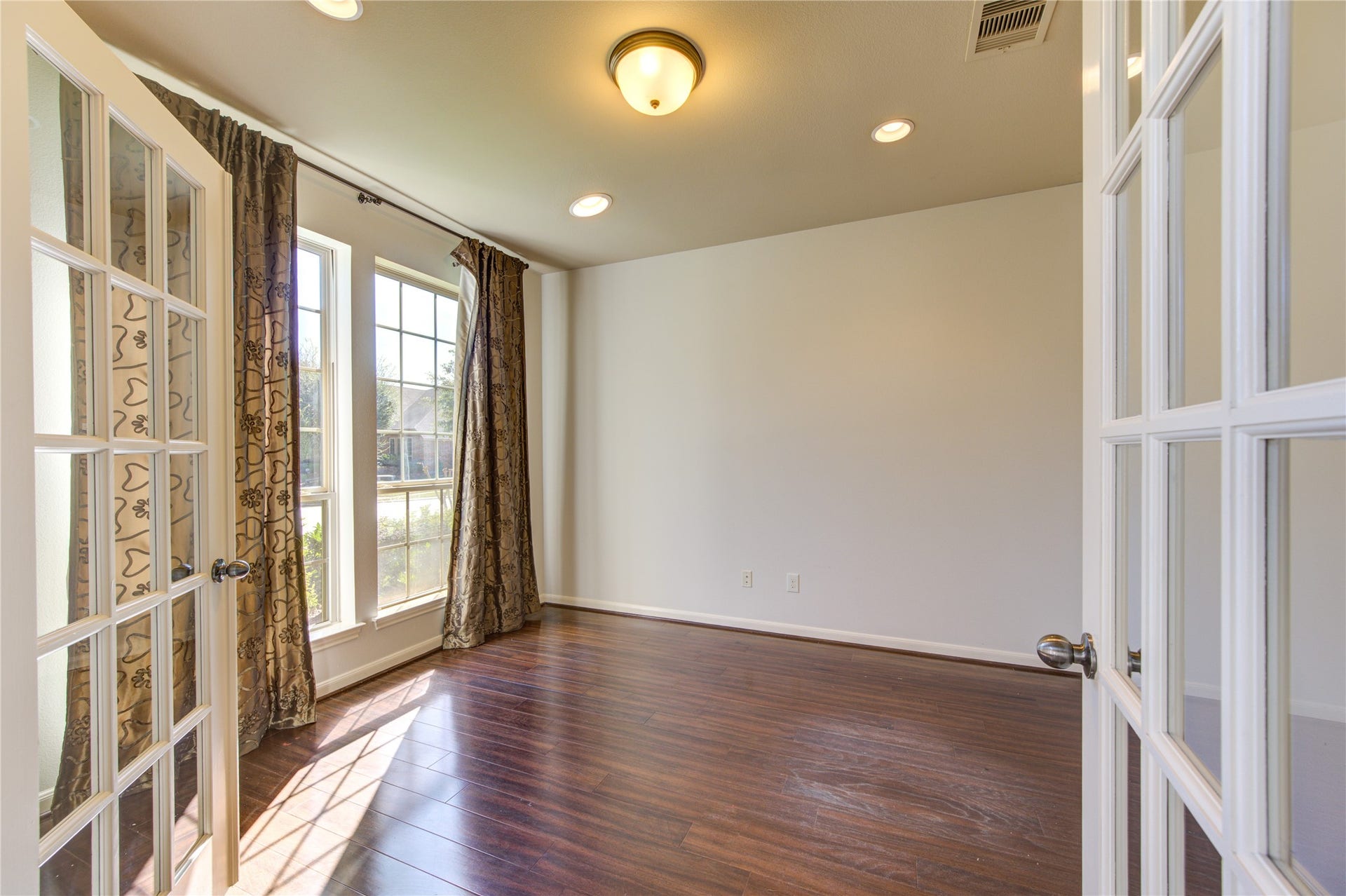 Wood floor and extra lighting in study with french doors.