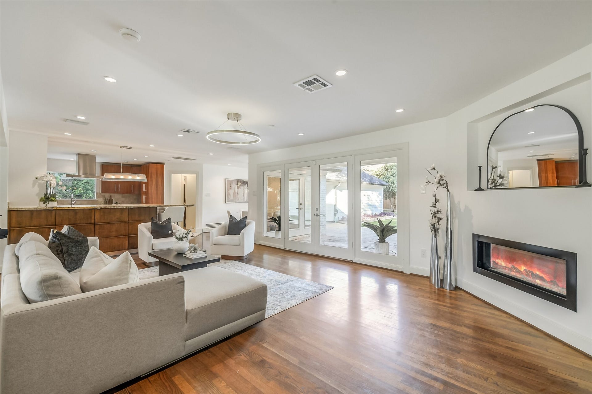 Open-concept living room with a seamless flow into the kitchen and French doors that open to the beautiful backyard.