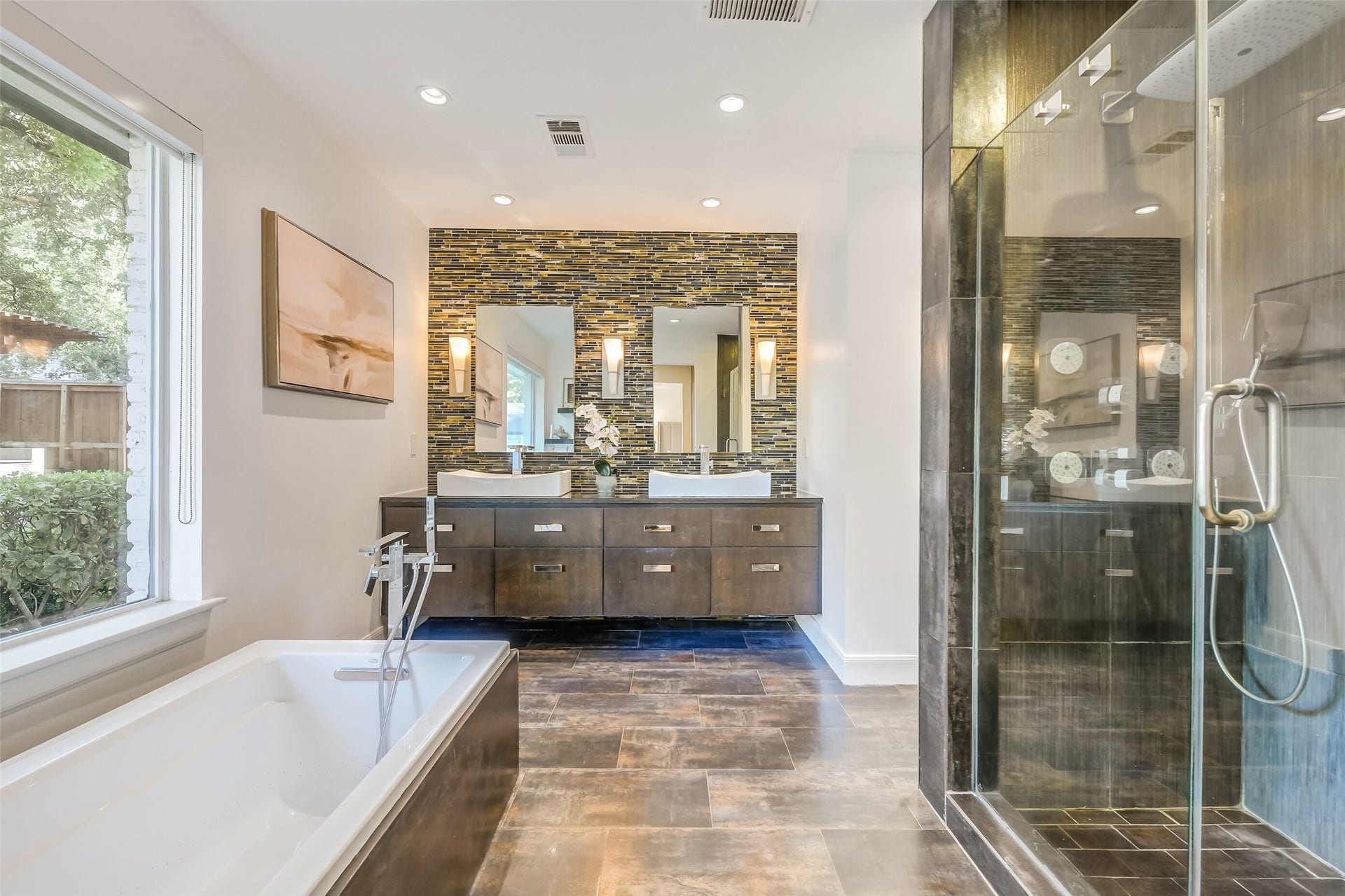 Spa-inspired primary bath featuring dual vessel sinks, floating vanity, decorative mosaic tile accent wall, soaking tub, and an oversized glass-enclosed shower.