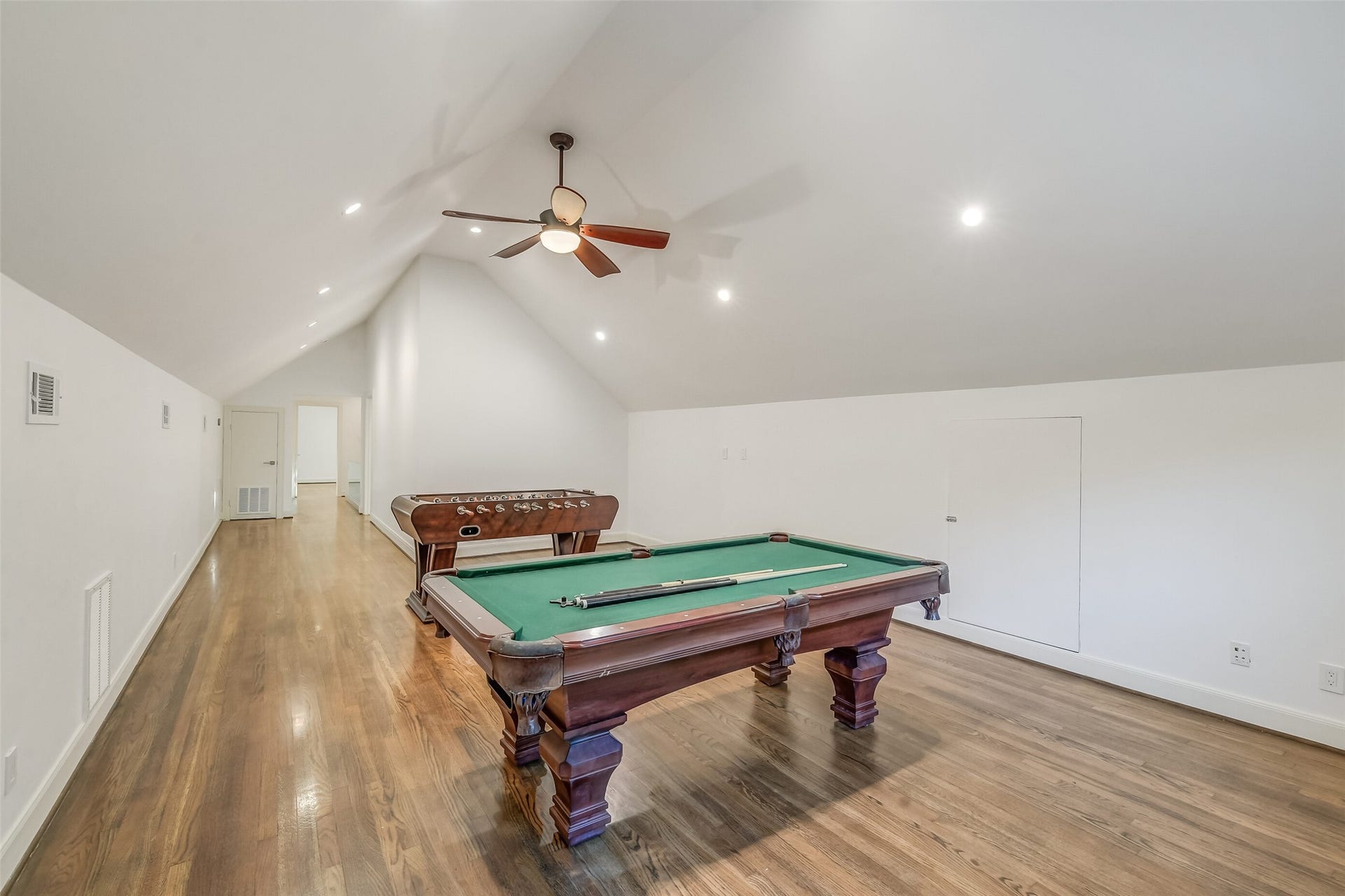 Generously sized game room featuring vaulted ceilings, hardwood floors, and a flexible layout ideal for a variety of recreational activities.