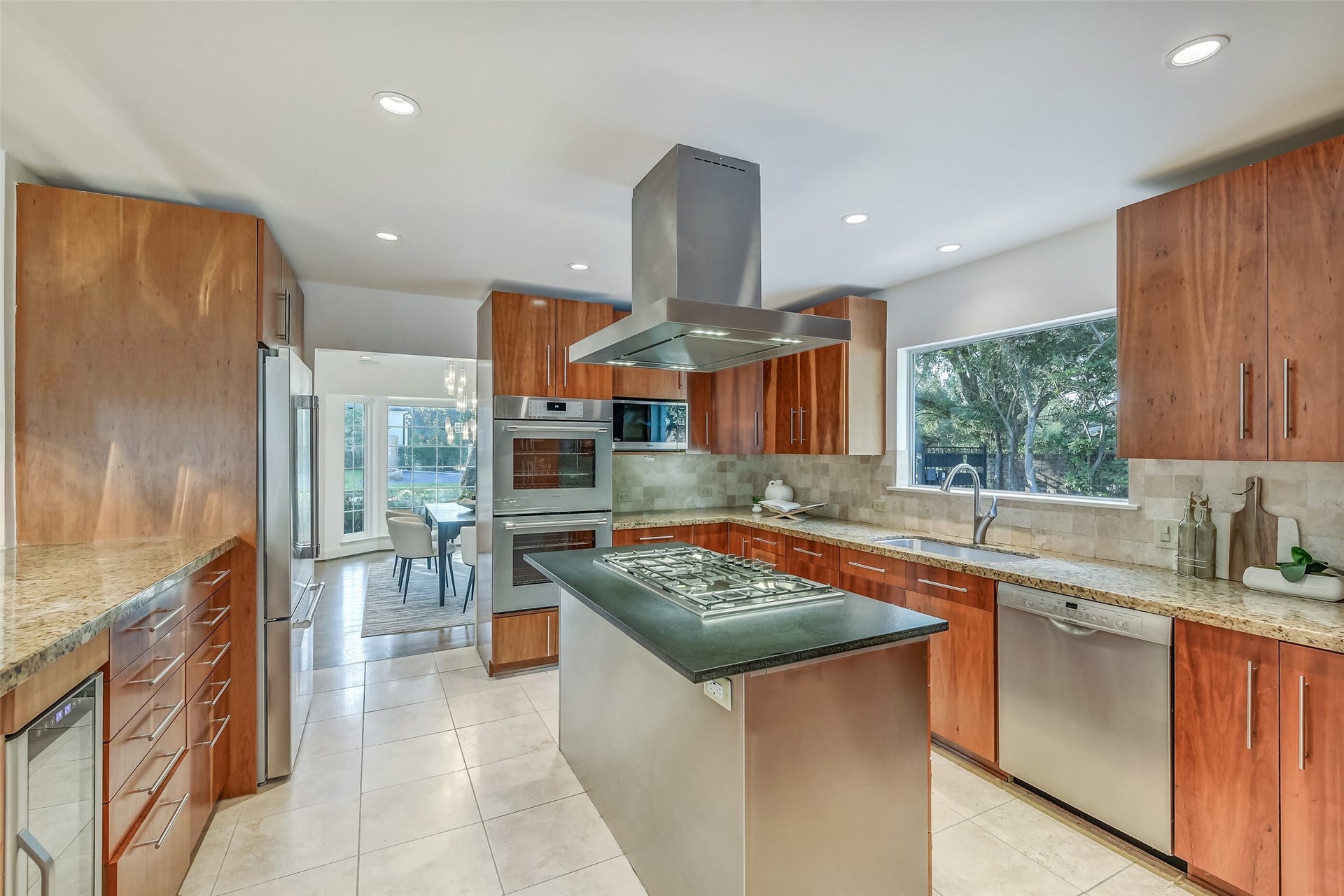 Beautifully appointed kitchen featuring a center island, premium Thermador appliances, including a gas cooktop, stainless steel vent hood, double ovens, and refrigerator, complemented by abundant cabinetry and generous counter space.