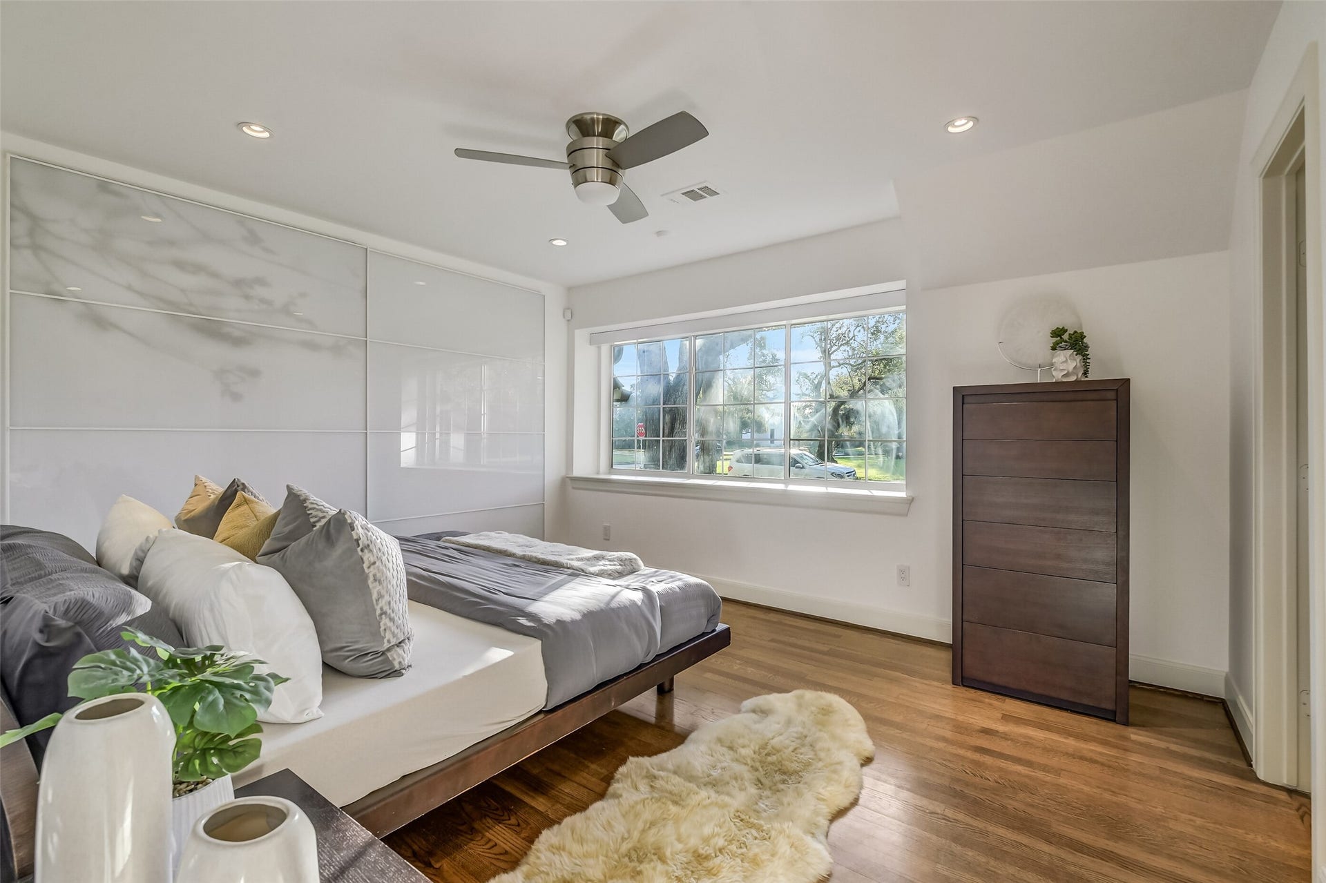 Spacious first-floor secondary bedroom featuring en-suite bathroom, recessed lighting, a generous reach-in closet, and a large window that fills the room with natural light, creating a bright and inviting retreat.