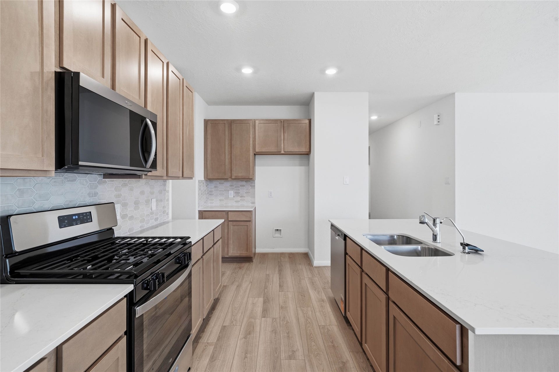 3039 Cronus Way, Fresno, TX 77545 This bright, open kitchen is a chef's delight, complete with a large island, granite countertops, Woodmont Cody cabinets in Ginger stain and accented with matte black hardware, Whirlpool stainless steel appliances, and modern Daltile backsplash.