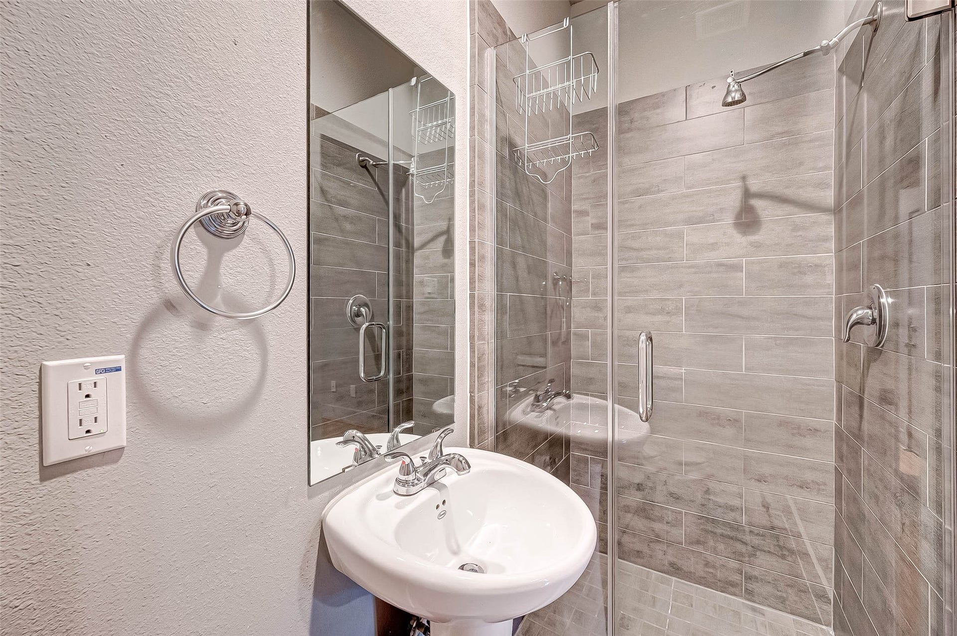 5111 Cornish Street, Houston, TX 77007 Modern bathroom featuring a sleek glass-enclosed shower with stylish gray tile, complemented by a chic pedestal sink and contemporary fixtures.