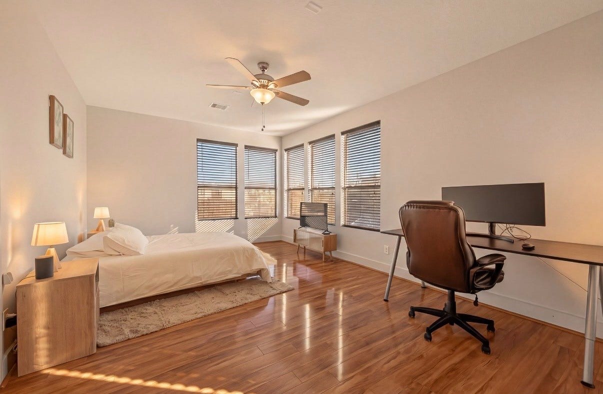 5111 Cornish Street, Houston, TX 77007 Spacious Master bedroom on THIRD floor with abundant natural light, featuring sleek hardwood floors, a cozy bed, and a convenient workstation.