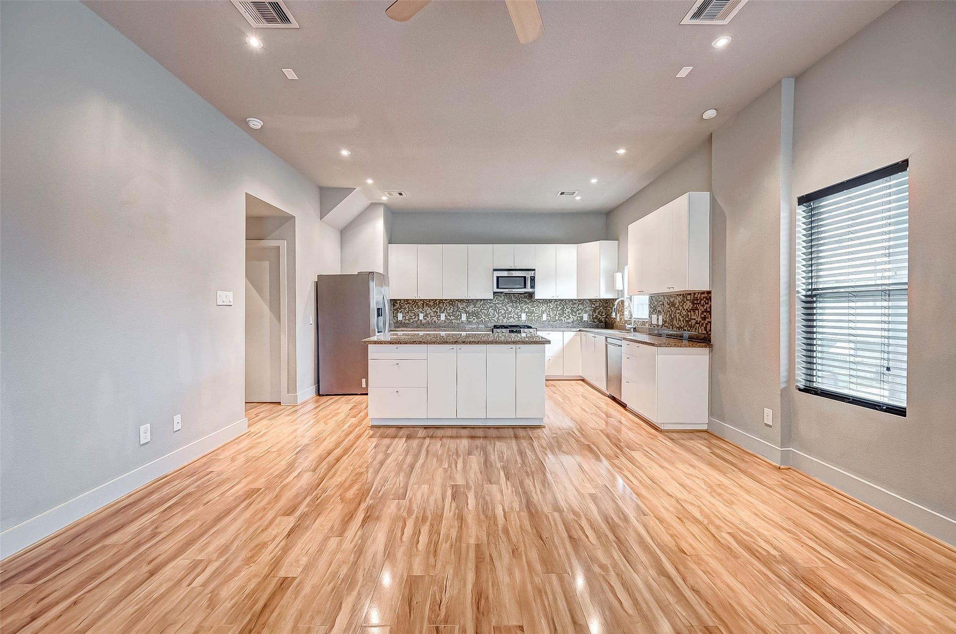 5111 Cornish Street, Houston, TX 77007 Spacious open-concept kitchen with modern white cabinetry, stainless steel appliances, and elegant wood flooring, perfect for entertaining and daily living.