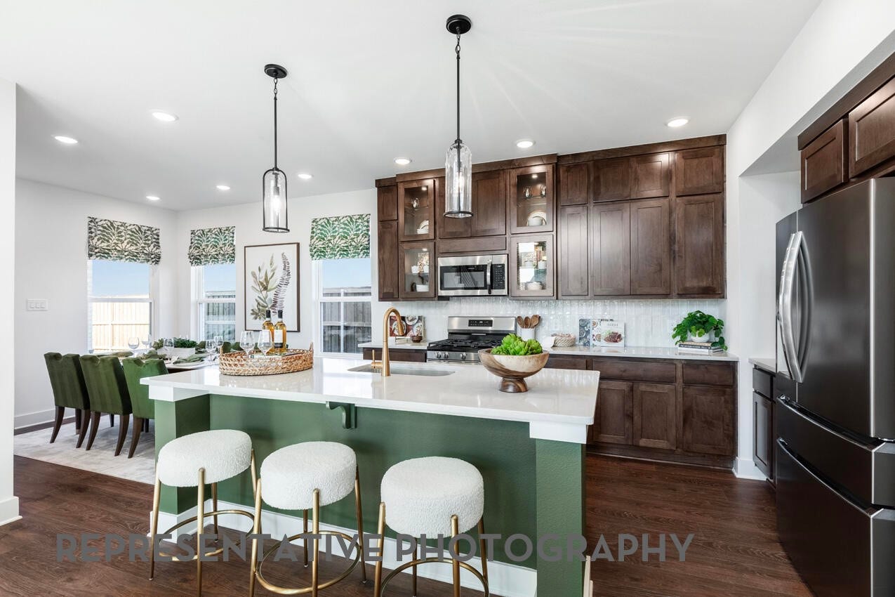 3435 Loam Lane, Richmond, TX 77406 A stunning kitchen showcases beautiful cabinetry, a large central island, abundant natural light from windows, and bright lighting that enhances its warm and inviting design.