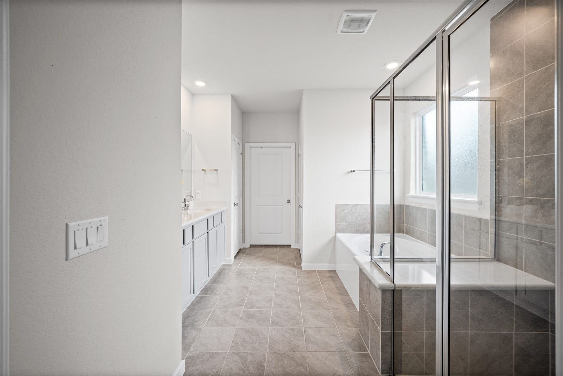 A relaxing owners bath pairs a soaking tub with a separate glass-enclosed shower for a comfortable retreat.