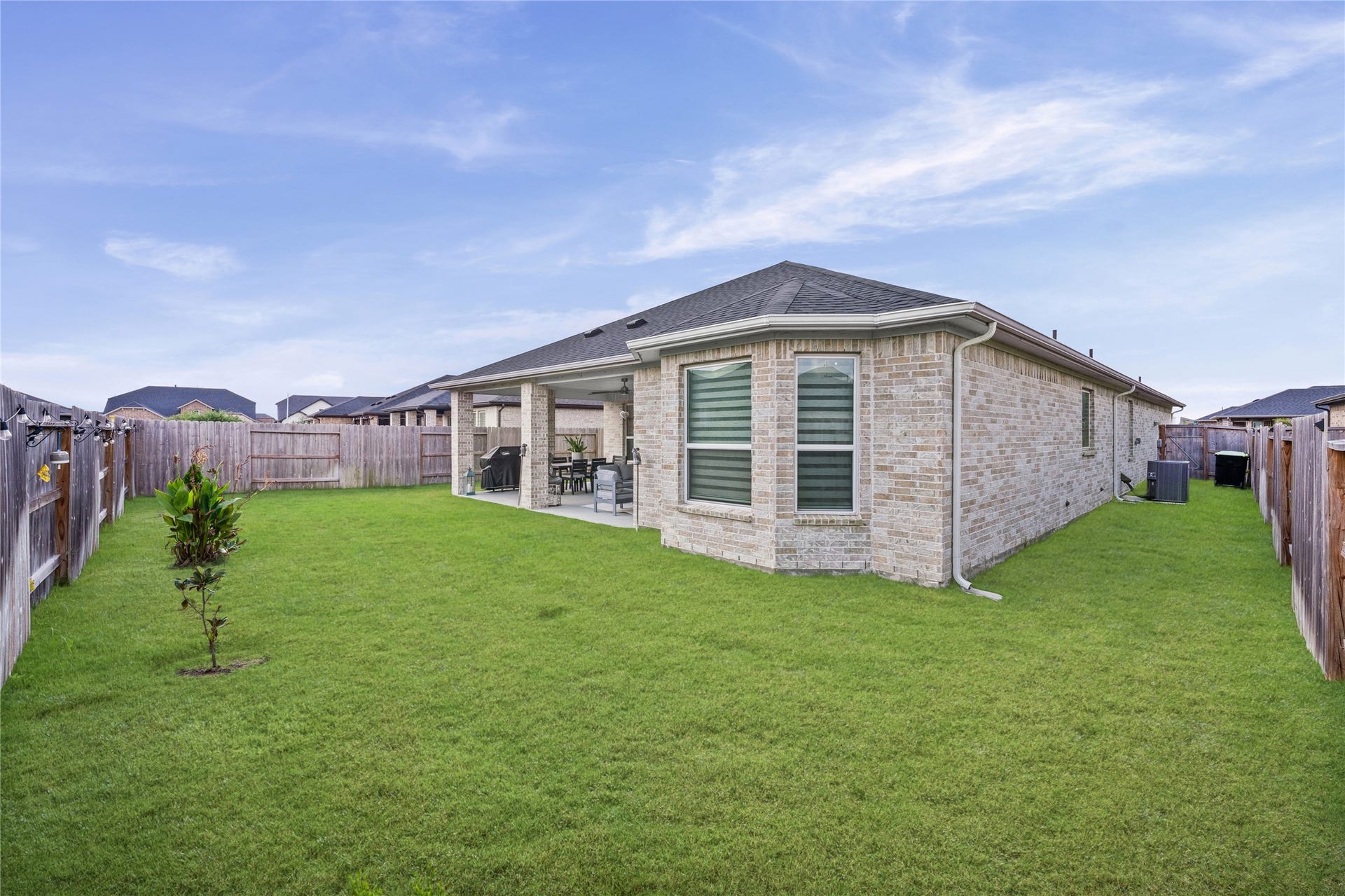 Another backyard view highlights the generous green space and connection to the covered patio.