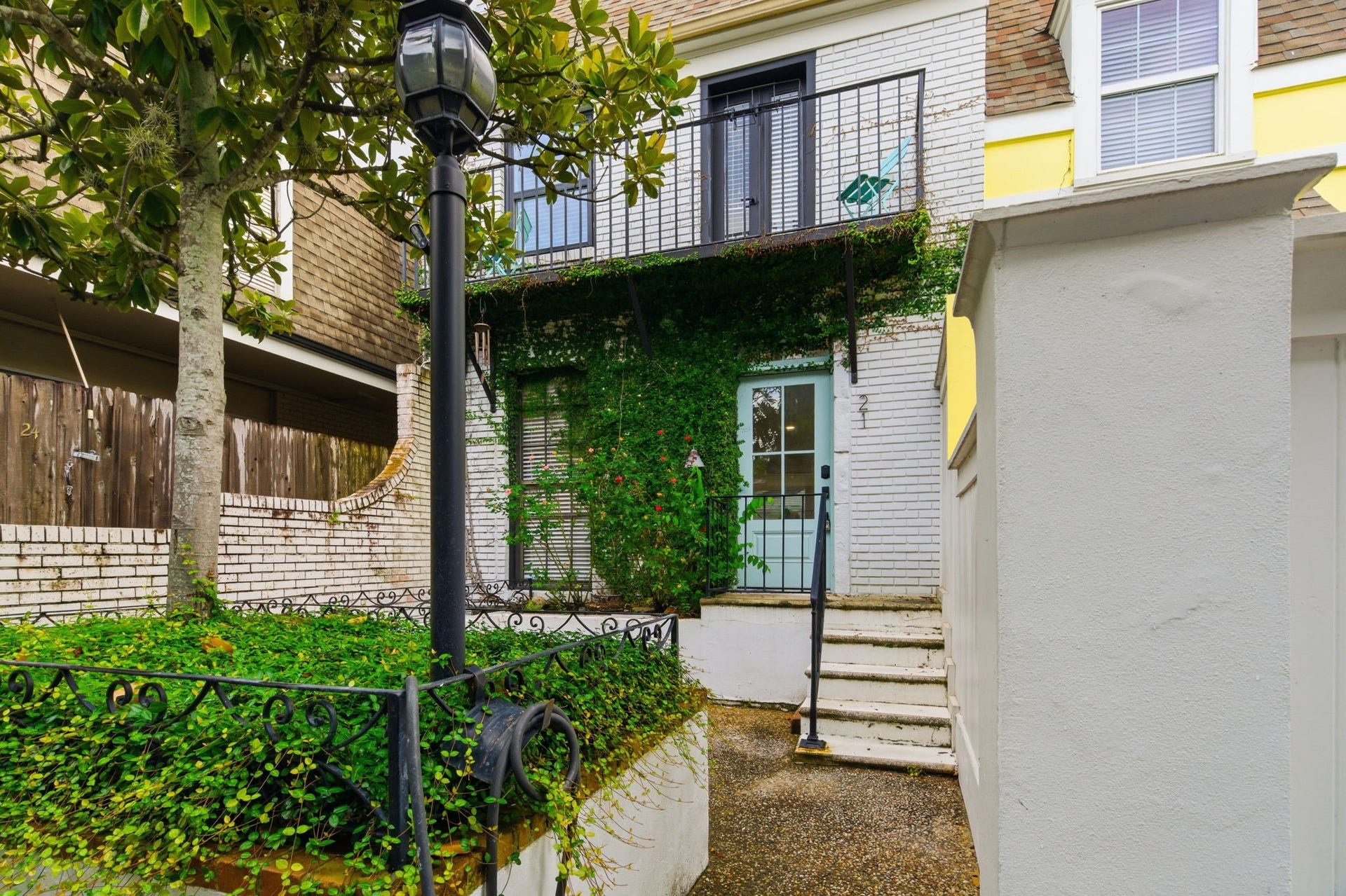 811 Lovett Boulevard, #21, Houston, TX 77006 The homes courtyard entry is framed by established greenery, flowering plants, and classic brickwork.