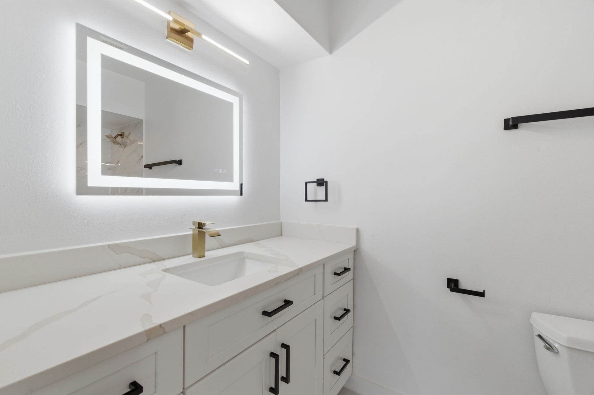 811 Lovett Boulevard, #21, Houston, TX 77006 Clean lines, mixed metal finishes, and an illuminated mirror give the primary bathroom a polished, modern look.